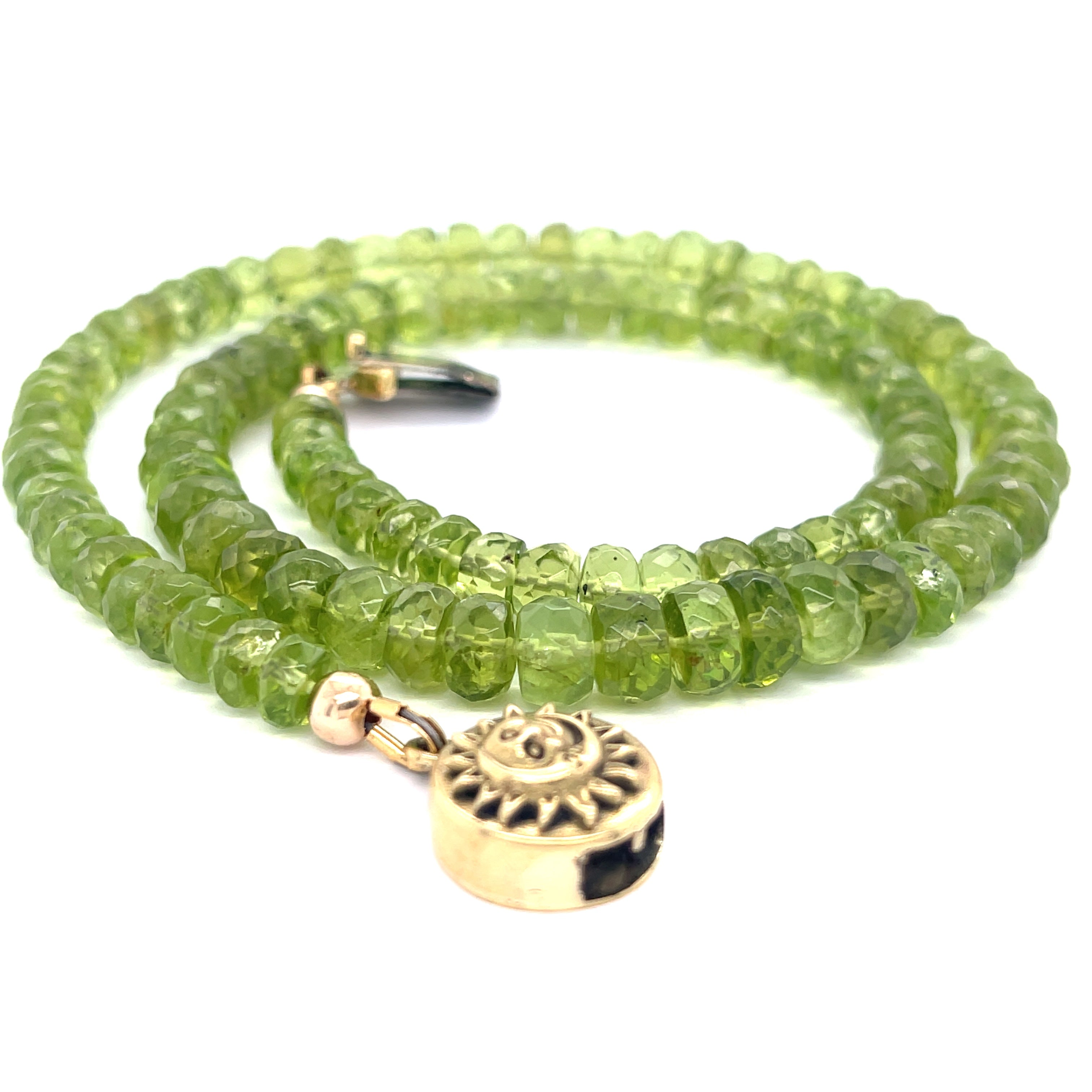 A green beaded peridot gemstone necklace with gold-filled findings and a sun and moon box clasp on a white background, spiral flat overview.