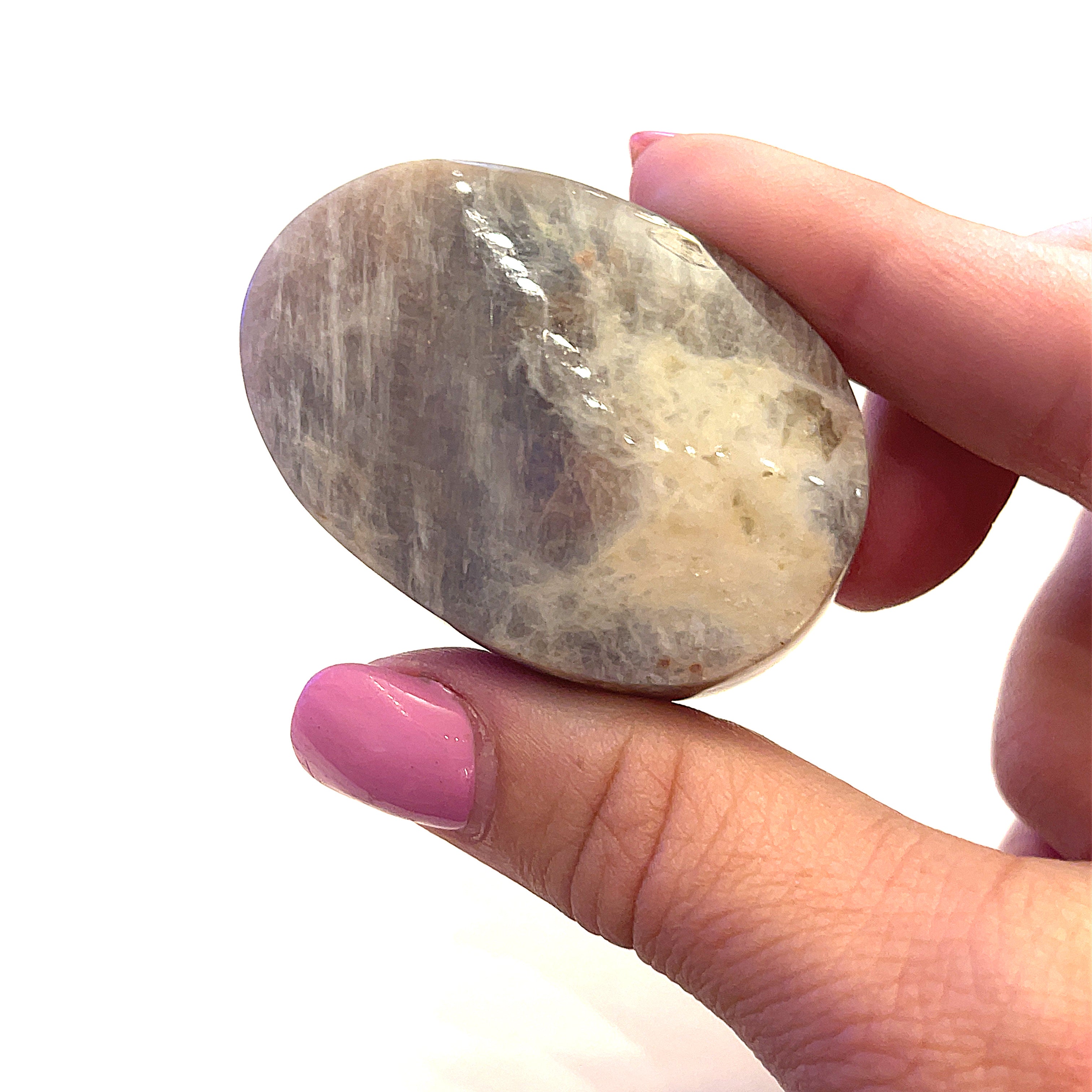 A grey moonstone palm stones displayed betweeen the models fingers on a white background front overview.