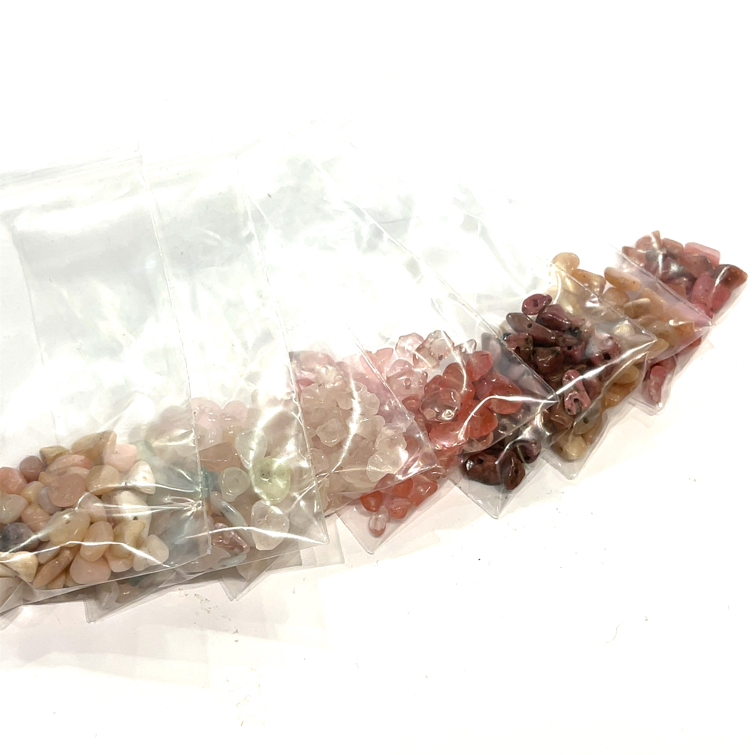 A group of pink, peach, brown rays of gemstone chip bags, on a white background, front view.