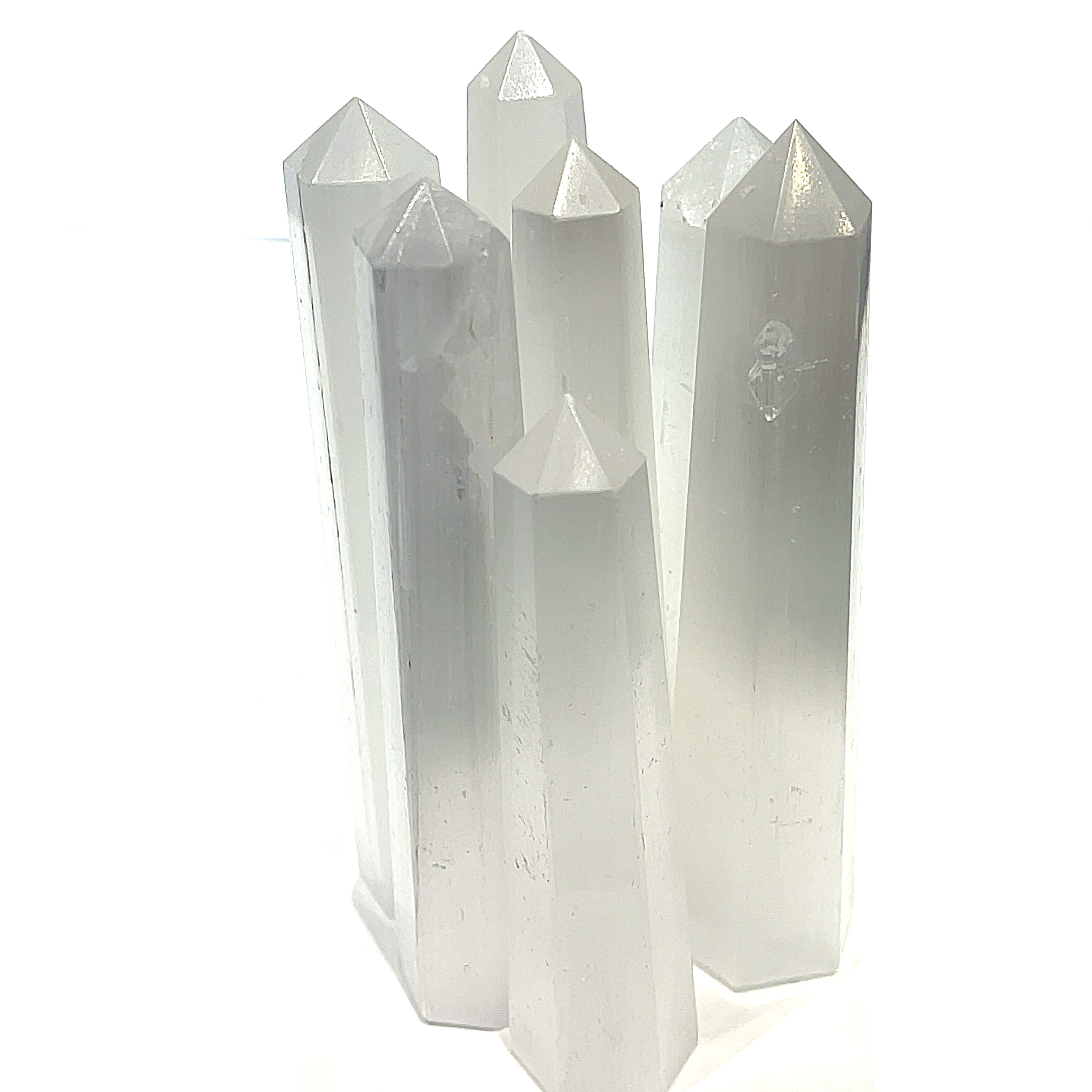 A group of selenite gemstone towers displayed together on a white background, front overview. 