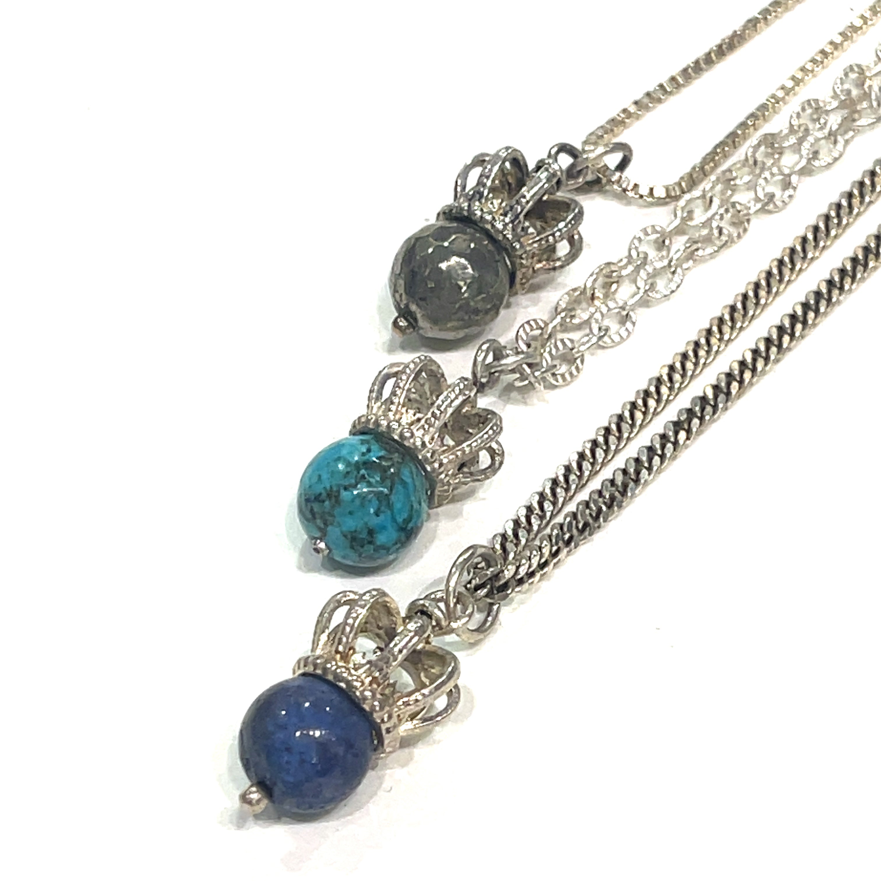 A group of three Sterling Silver Crown Pendant with pyrite, turquoise, and lapis lazuli gemstone on a white background, front overview. 