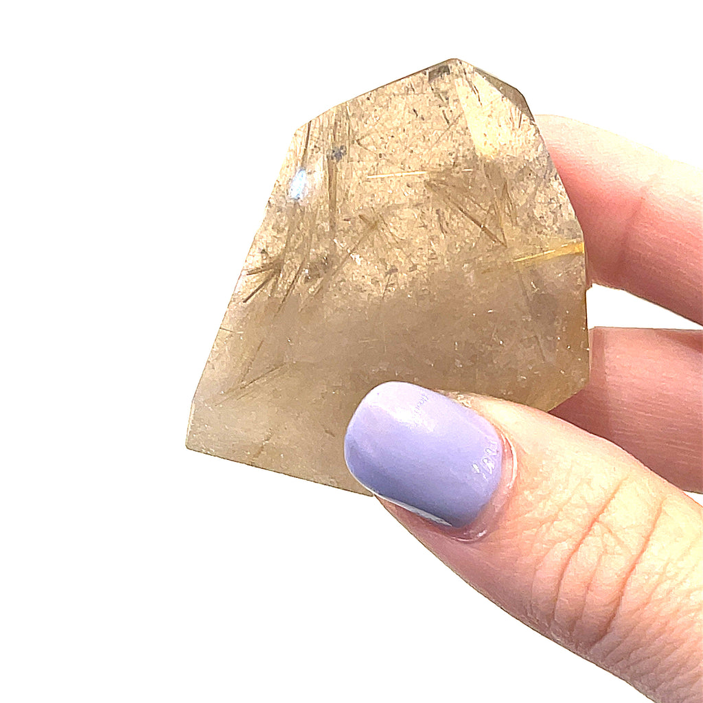 A hand holding a free-form Rutilated Quartz gemstone on a white background, front overview. 