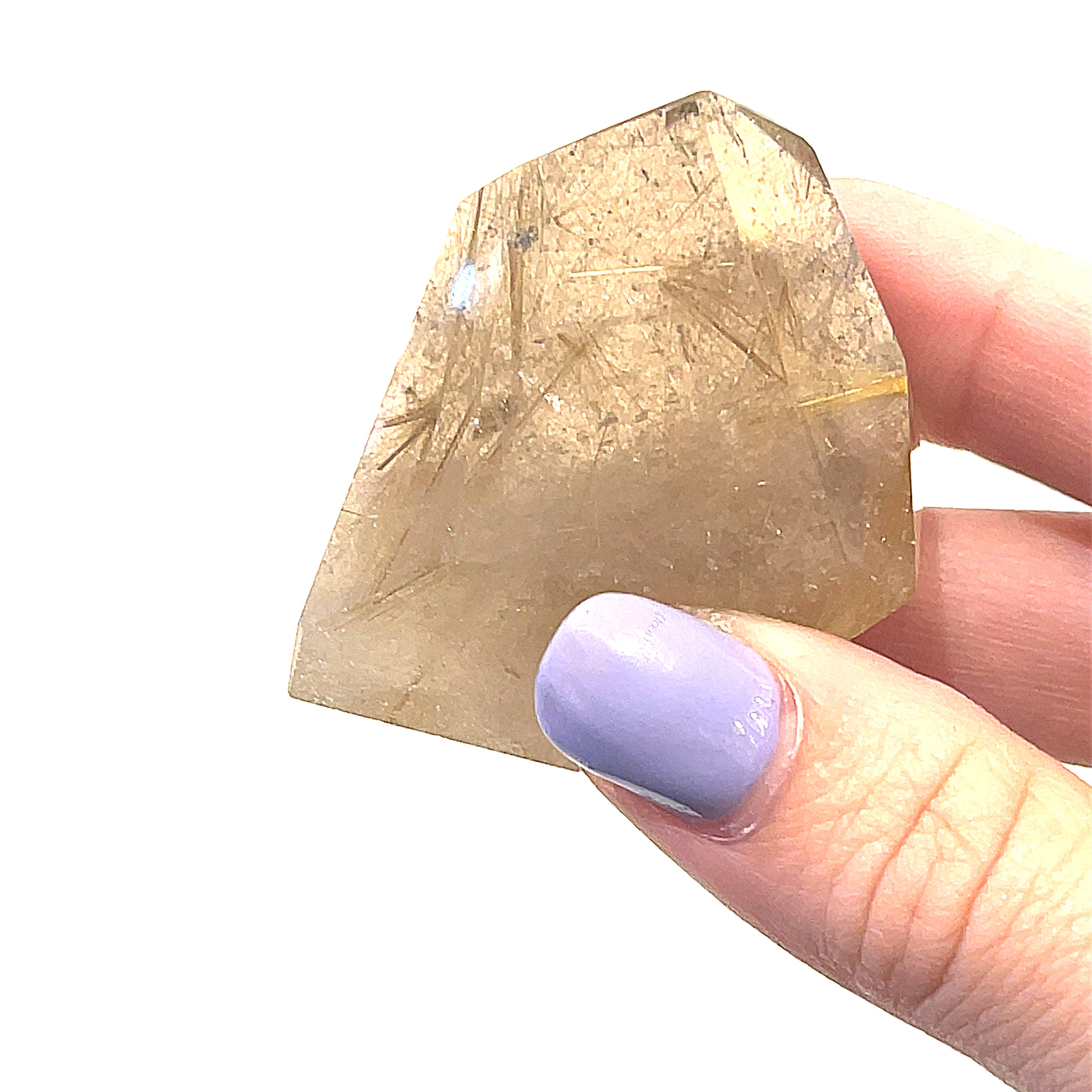 A hand holding a free-form Rutilated Quartz gemstone on a white background, front overview. 