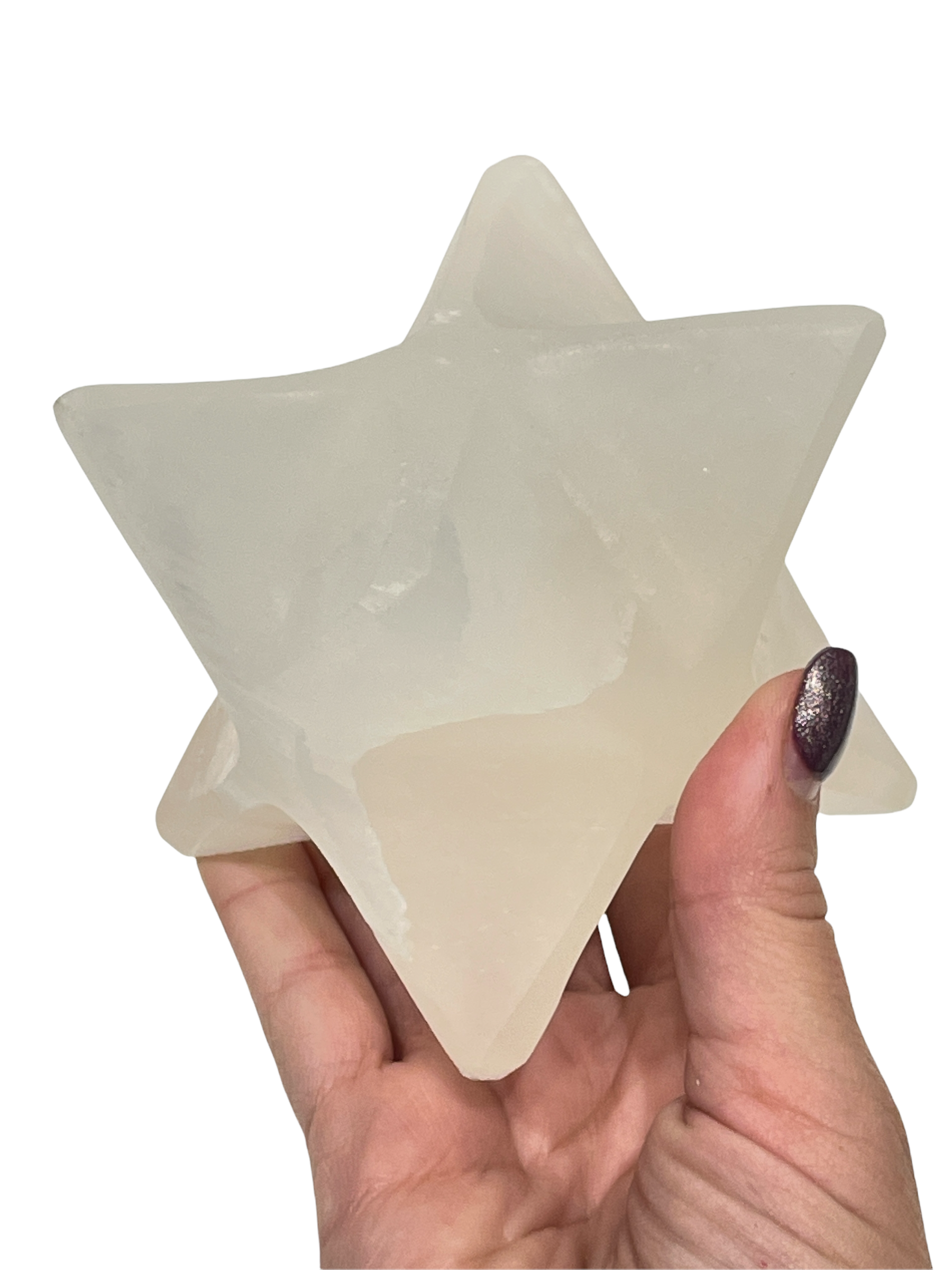 A hand holding a transparent selenite merkaba gemstone against a white background, front view. 