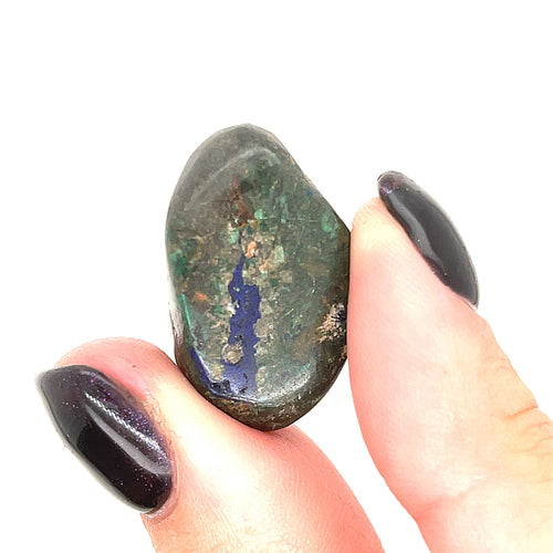 A hand holding a tumbled Azurite gemstone with visible Malachite inclusions on a white background, front view.