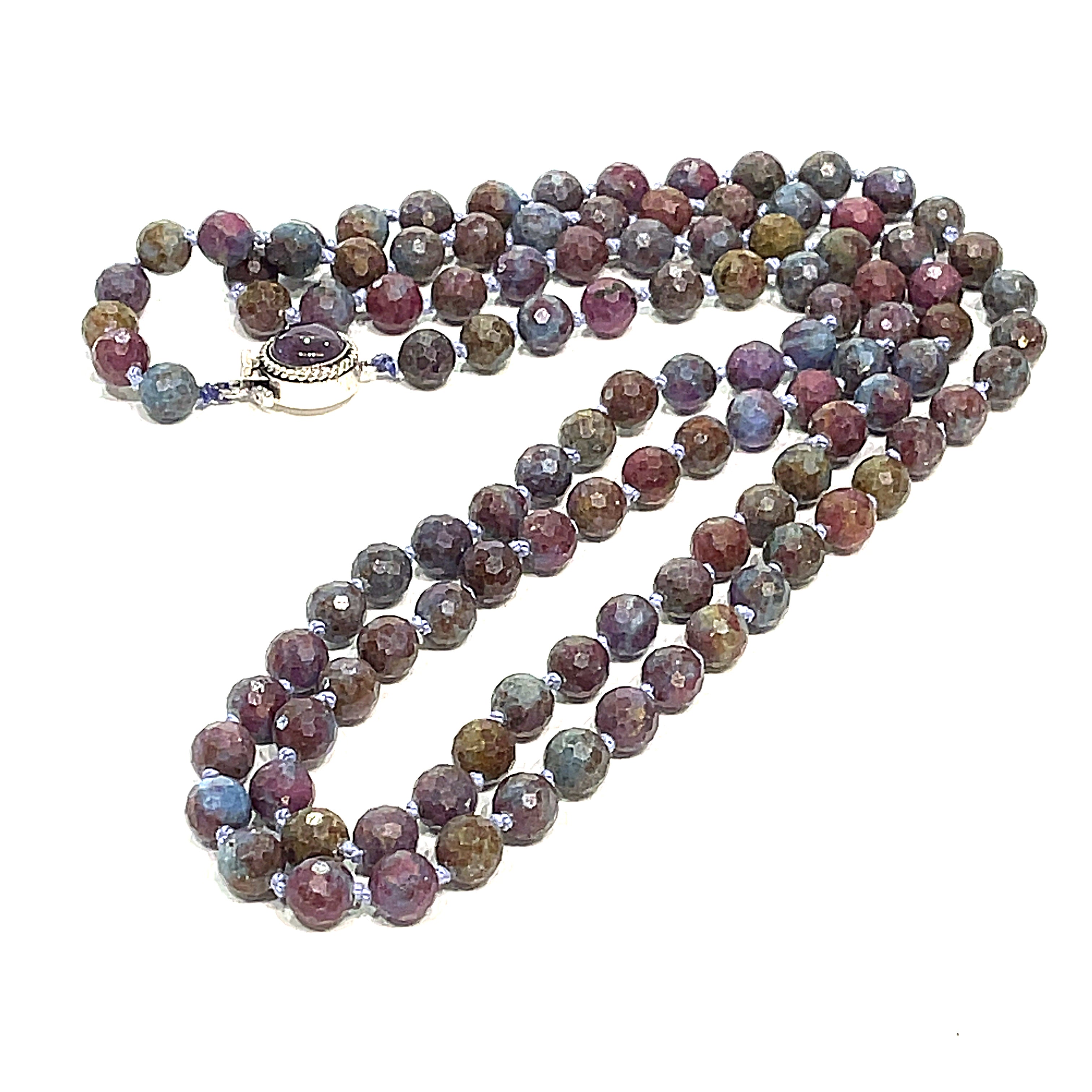 A knotted Ruby Kyanite gemstone necklace with a sterling silver amethyst box clasp, beads are 6mm faceted round, long diagnoal, close-up, overview on a white background.