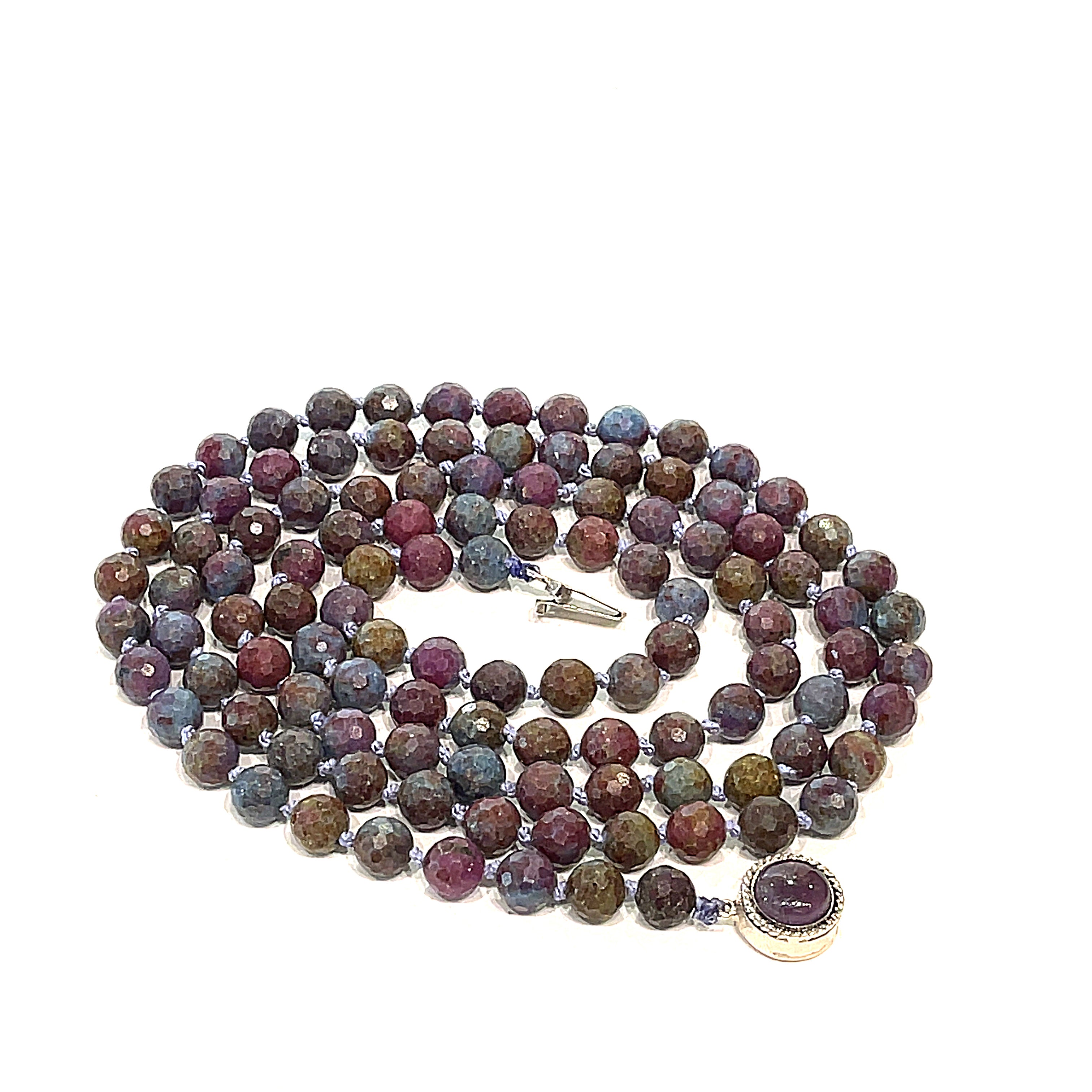 A knotted Ruby Kyanite gemstone necklace with a sterling silver amethyst box clasp, beads are 6mm faceted round, spiral close-up, overview on a white background.