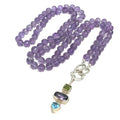 A knotted necklace featuring round Amethyst gemstones, a sterling silver heart clasp, and a silver gemstone pendant with Peridot and Blue Topaz, on a white background, center front overview. 