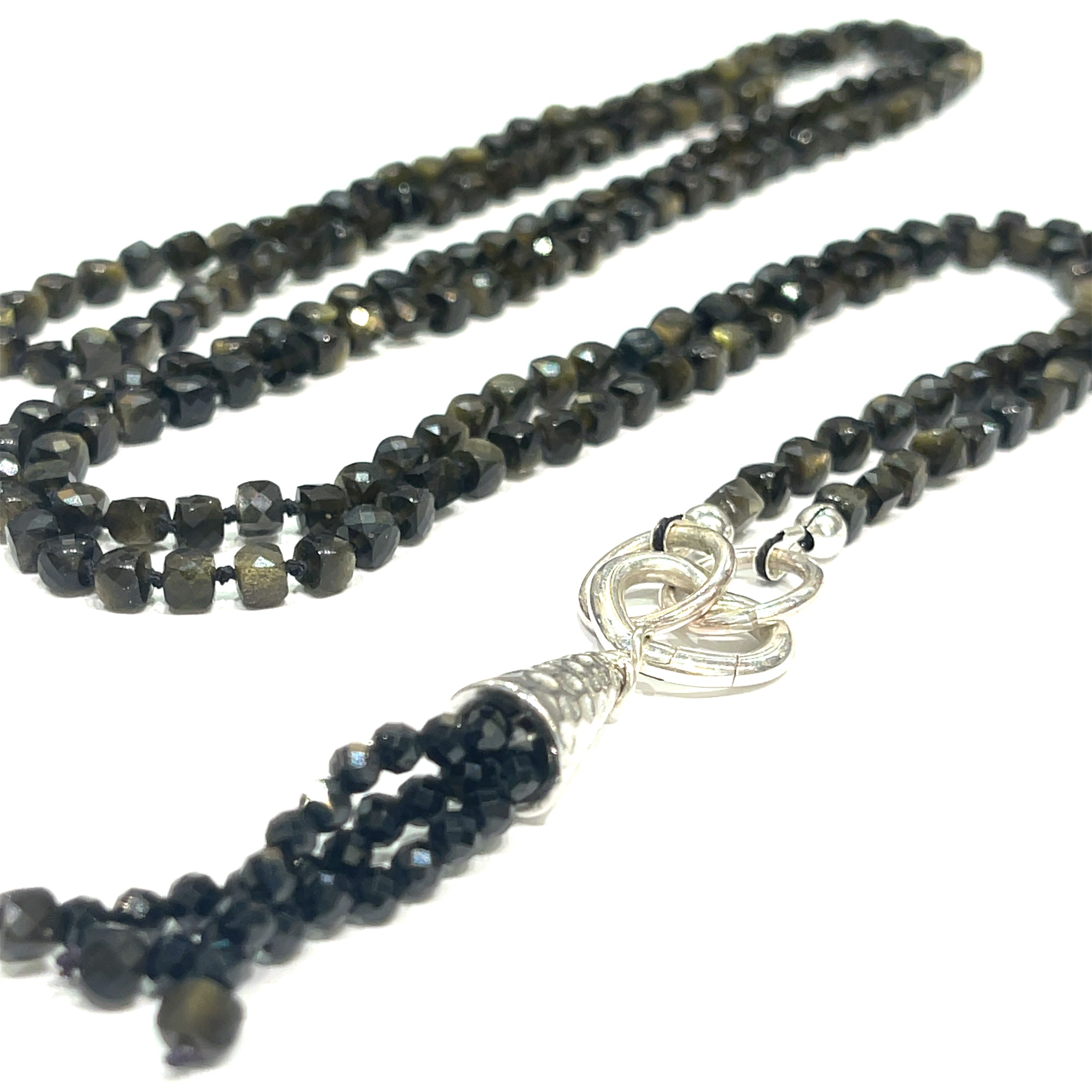 A knotted necklace made of Golden Sheen Obsidian gemstones with a tassel, featuring silver accents. On a white background, a long, center close up overview. 