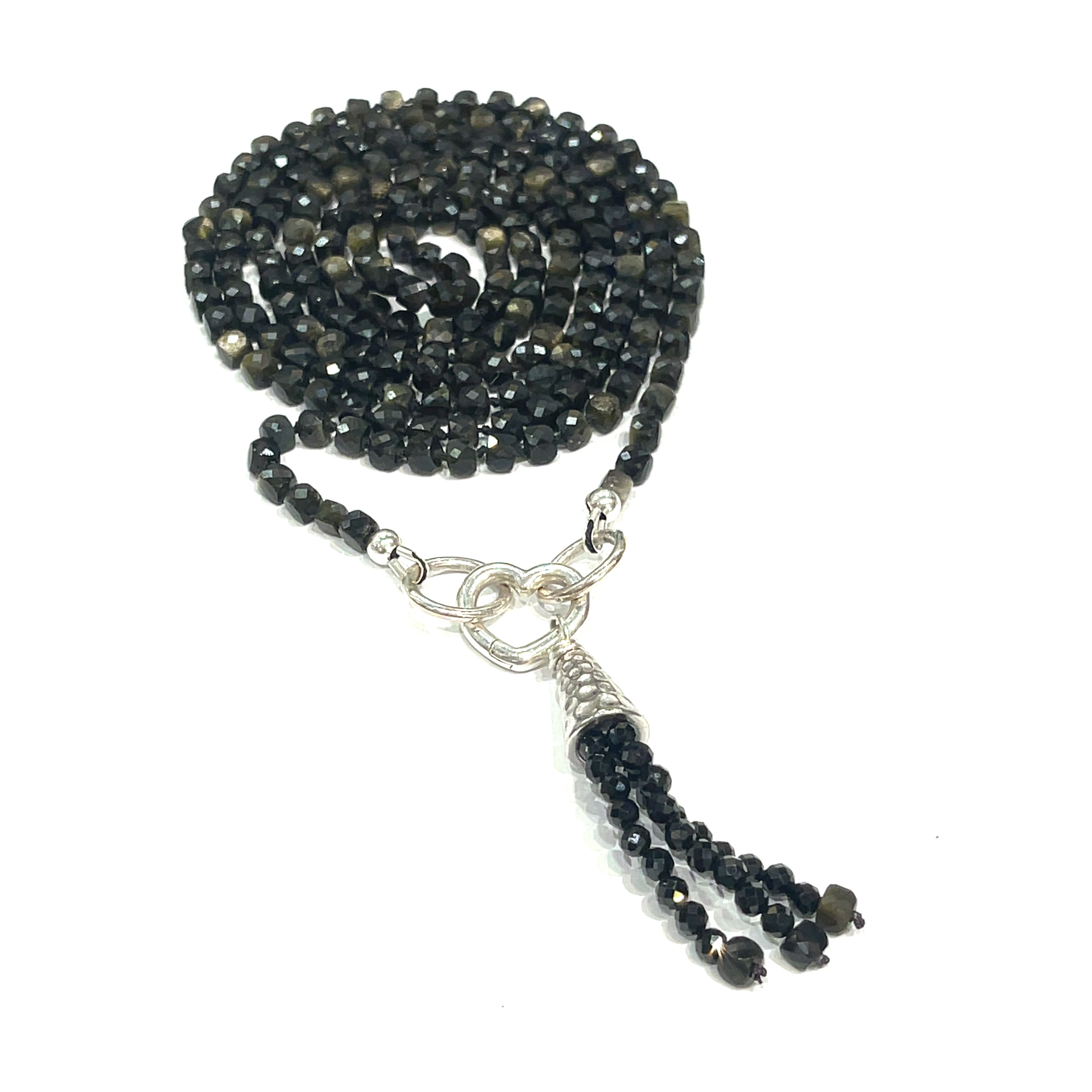 A knotted necklace made of Golden Sheen Obsidian gemstones with a tassel, featuring silver accents. On a white background, a spiral, center close up overview. 