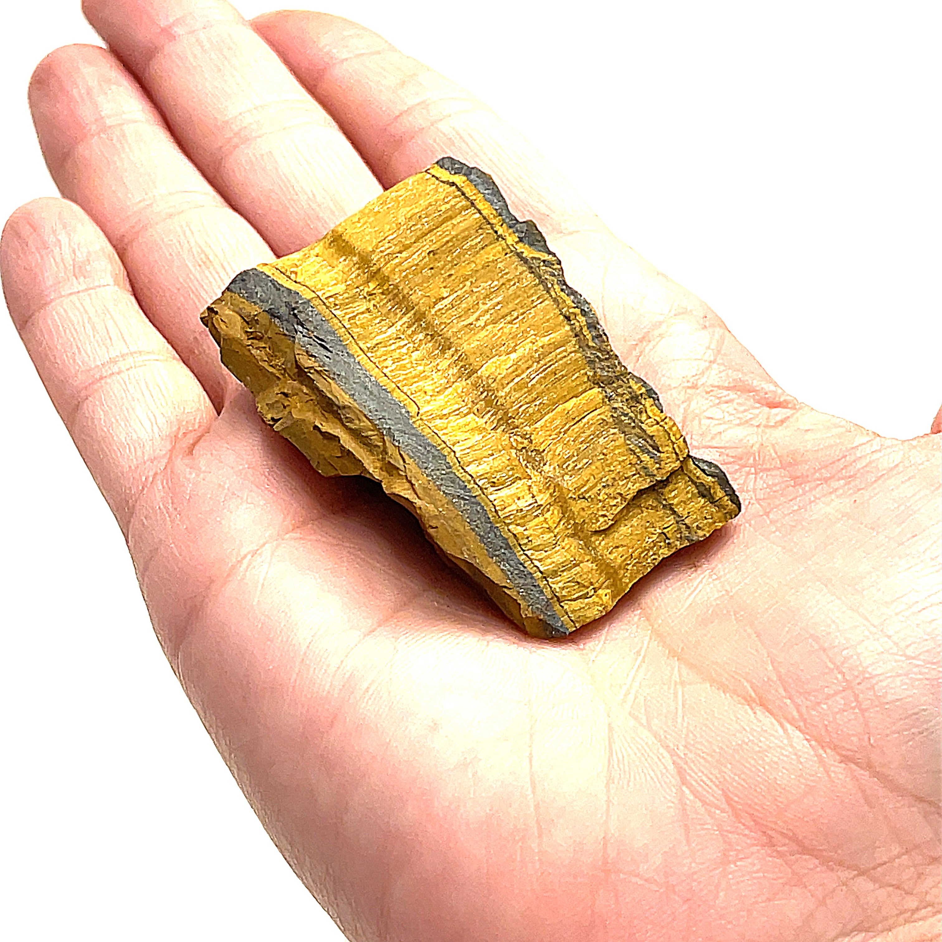 A medium pieces of raw golden tiger eye gemstones is displayed in a models finger tips, on a white background, in a front overview. 