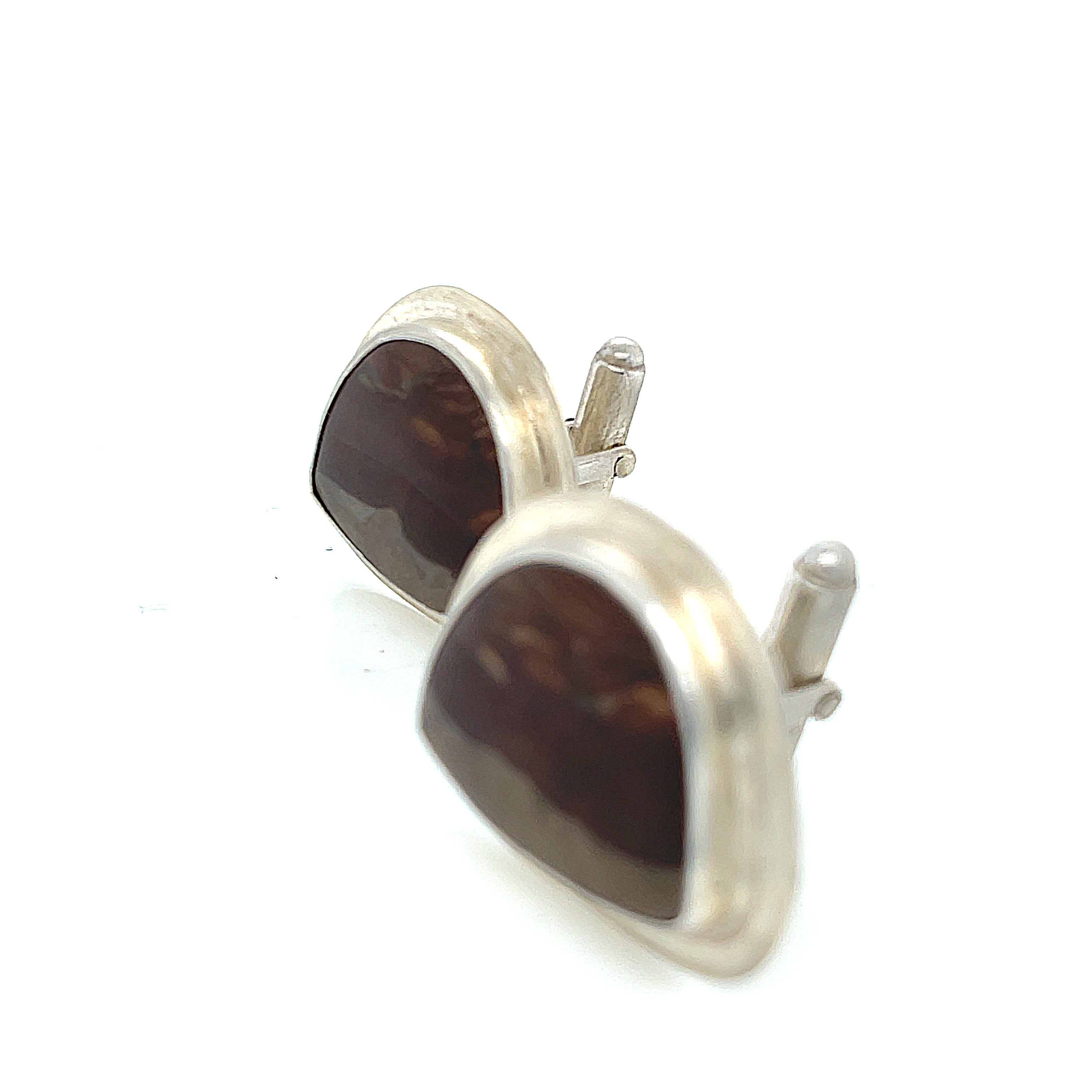 A pair of sterling silver cufflinks featuring rounded-triangle-shaped mookite jasper gemstones, bezel-set in a round sterling silver setting. On a white background, left-angle front view.