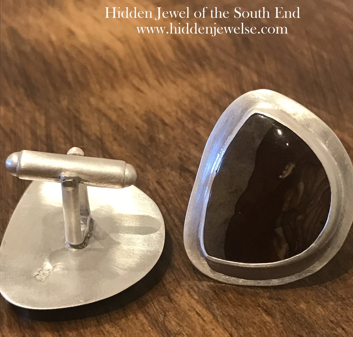 A pair of sterling silver cufflinks featuring rounded-triangle-shaped mookite jasper gemstones, bezel-set in a round sterling silver setting. On a wood background, close up one front and one back view.