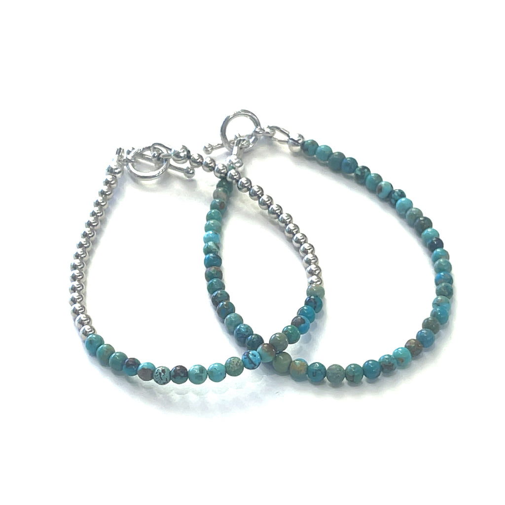 A pair of two Top-grade Turquoise 3mm gemstone smooth beads strung on durable Beadalon wire with a sterling silver toggle on a white background  front center view.