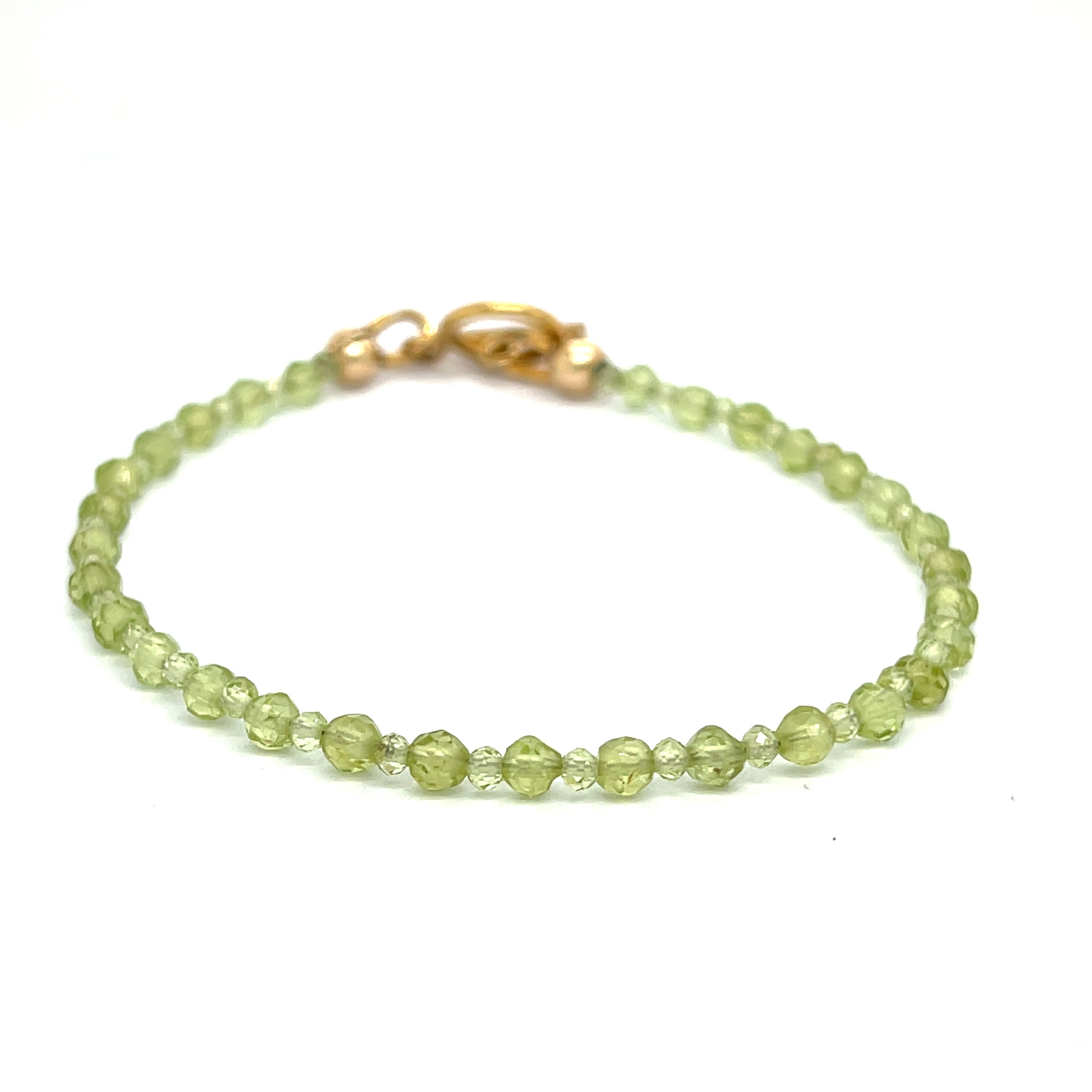 A peridot gemstone 2-3mm faceted round with a gold filled toggle on a white background front center overview.