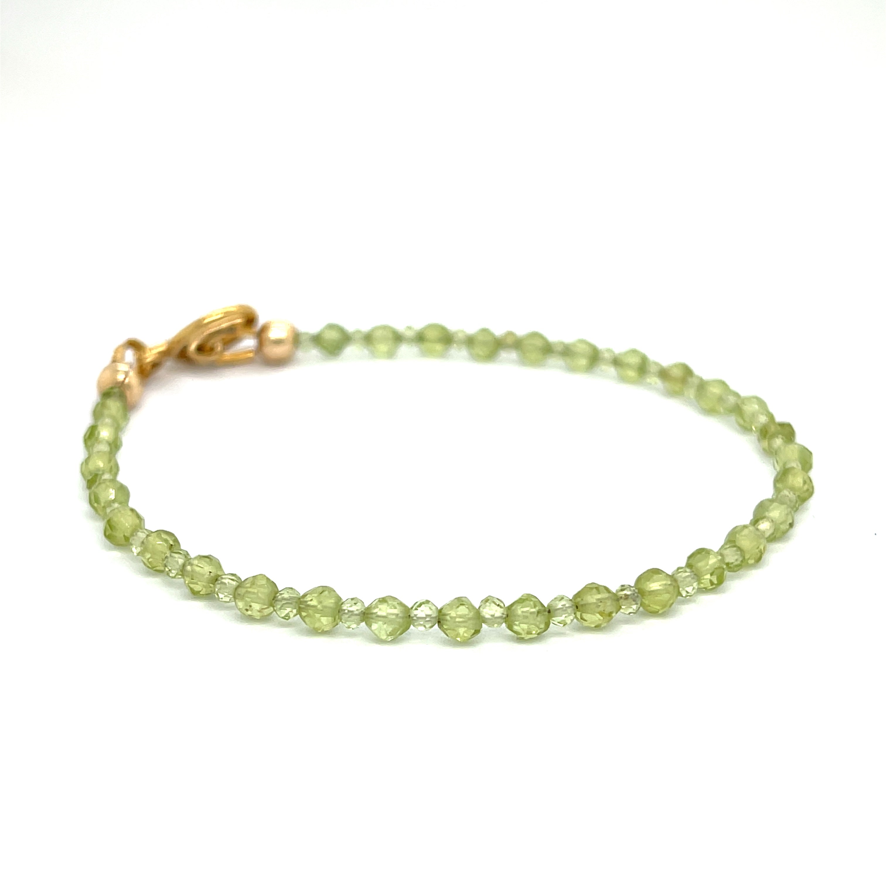 A peridot gemstone 2-3mm faceted round with a gold filled toggle on a white background front overview.
