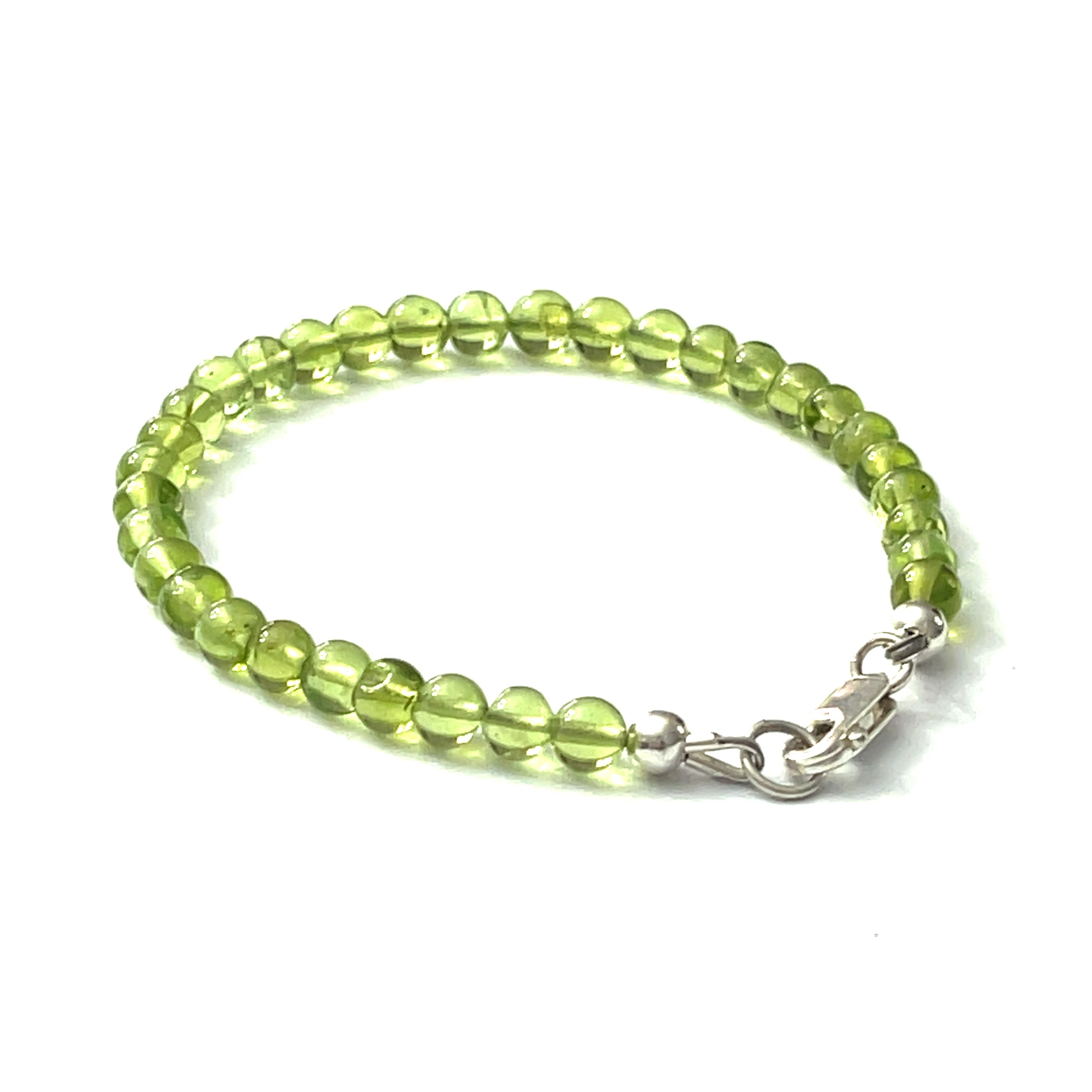 A peridot gemstone 6mm smooth round with a Sterling silver lobster claw on a white background back center overview.