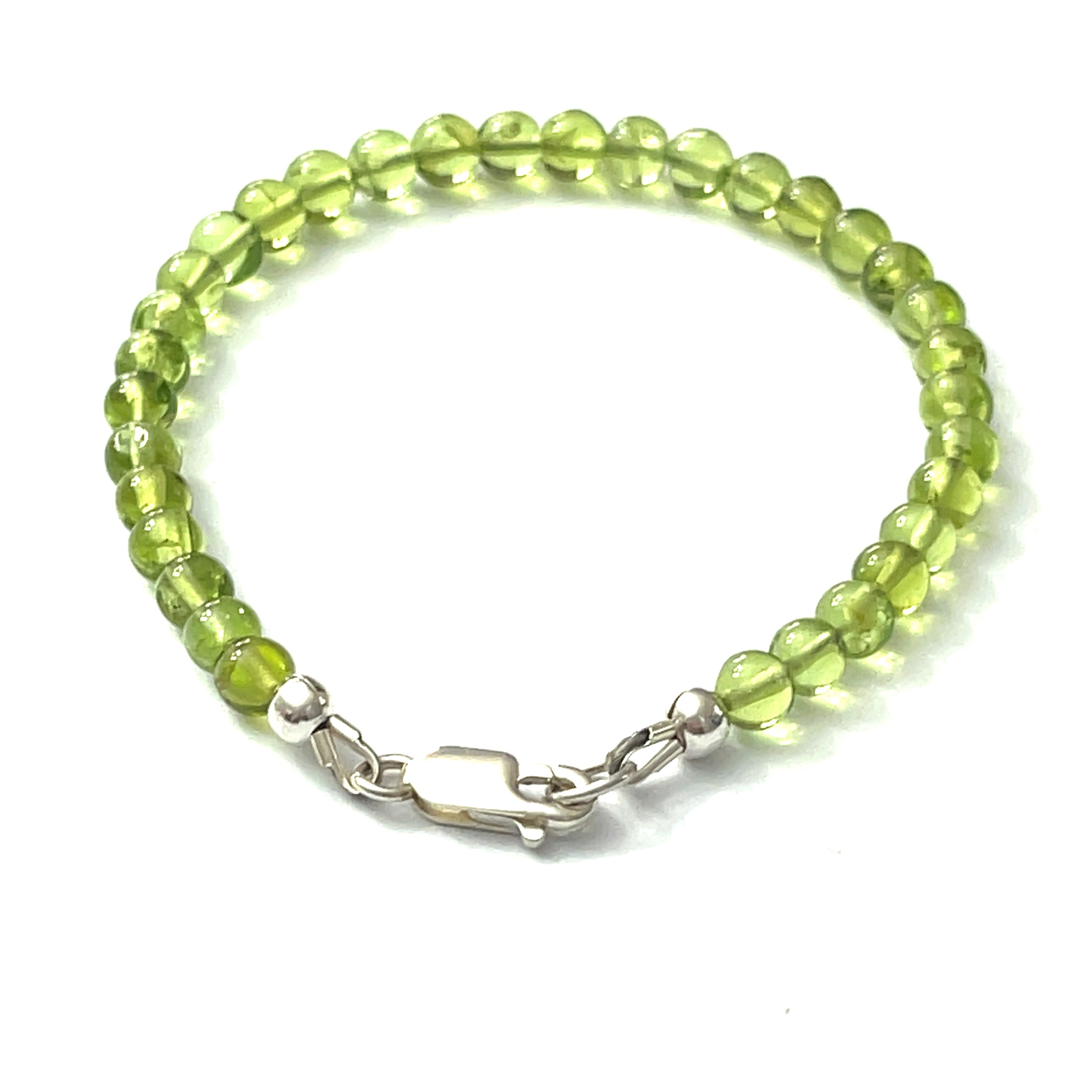 A peridot gemstone, 6mm smooth round, with a Sterling silver lobster claw on a white background, back overview.
