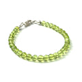 A peridot gemstone 6mm smooth round with a Sterling silver lobster claw on a white background front center overview.