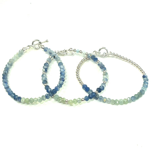 A photograph of two beaded gemstone bracelets, one with blue and green kyanite beads and another with a similar color scheme, both featuring sterling silver toggle clasps. On a white background, front overview. 