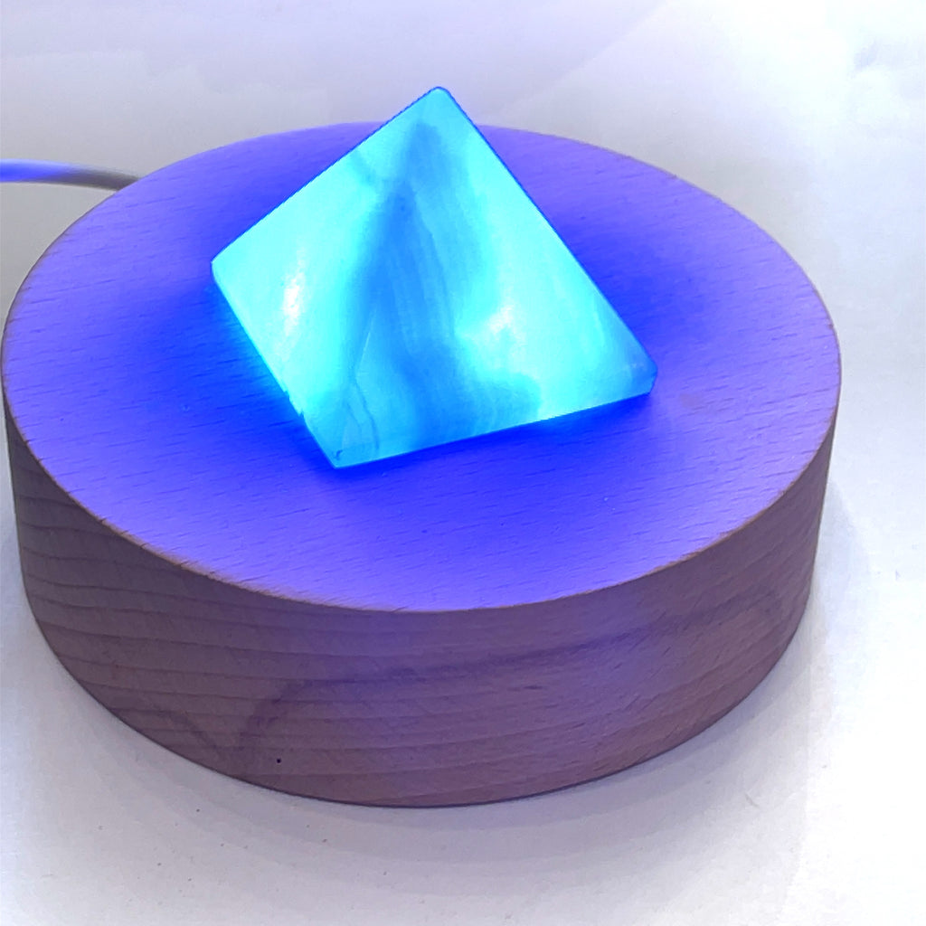A  pink Mangano Calcite pyramid-shaped gemstones displayed on a white background with a blue light. On a white background, center overview.