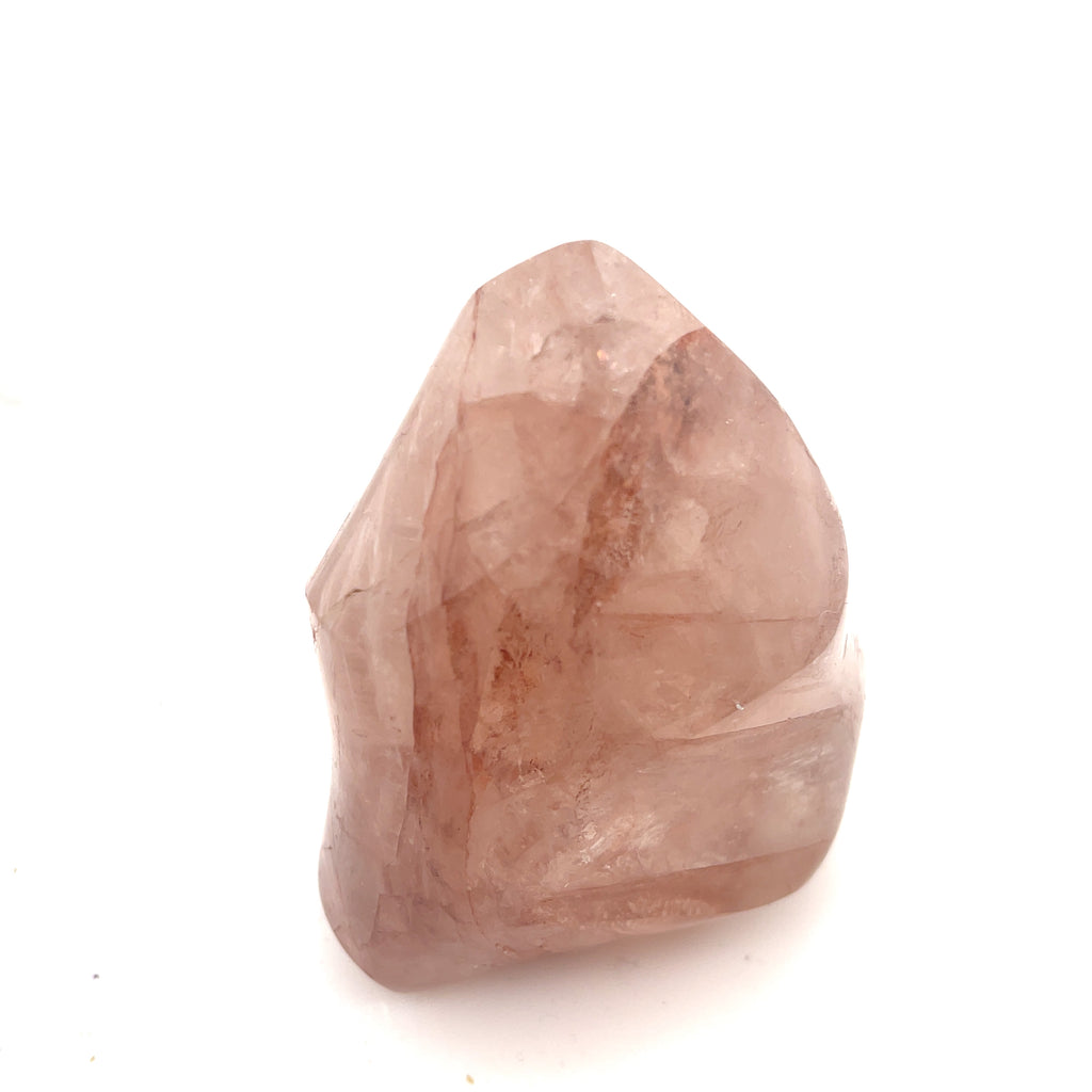 A polished Fire Quartz gemstones with a flame-like carving and a pink to red gradient on a white background front close up view.
