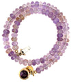 A purple ametrine beaded gemstone necklace with a gold-filled fluorite box clasp in a spiral, close-up overview on a white background. 