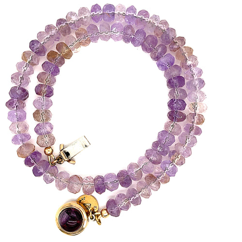 A purple ametrine beaded gemstone necklace with a gold-filled fluorite box clasp in a spiral, close-up overview on a white background. 
