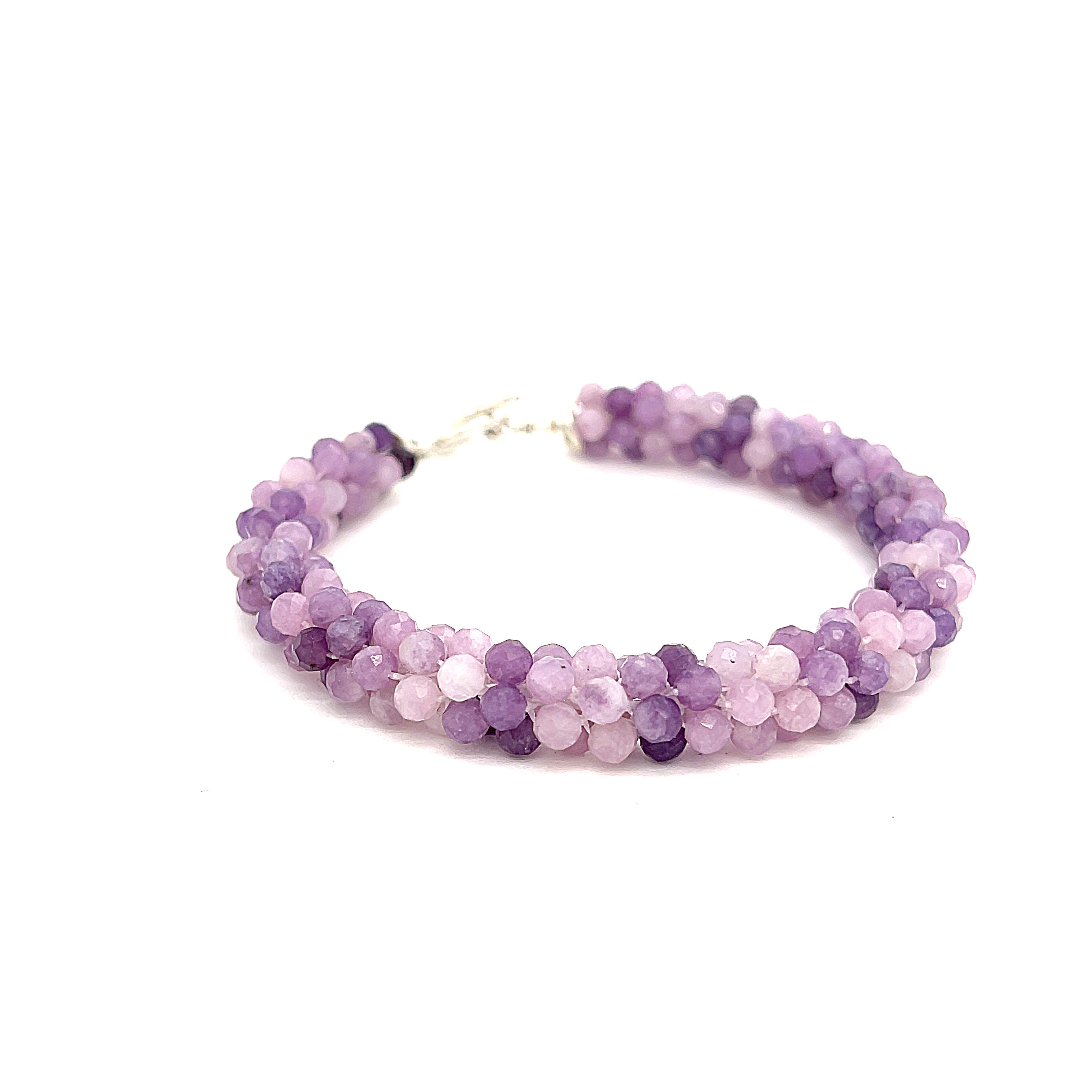 A purple sugilite gemstone bracelet with a sterling silver simple circle toggle, crocheted into a tubular pattern on a white background, front overview. 