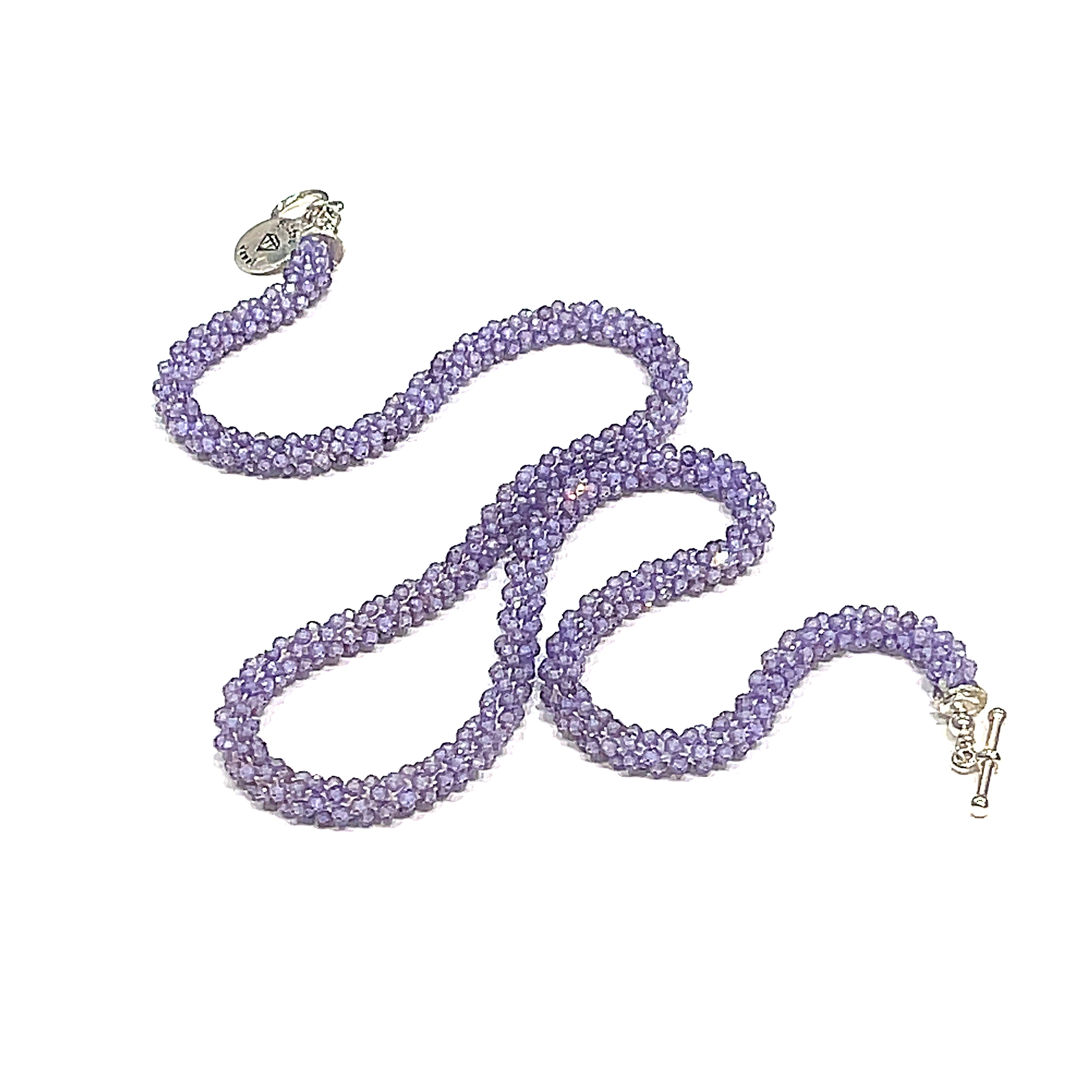 A purple zircon gemstone crocheted necklace with a sterling silver toggle, on a white background. A long front diagonal overview. 