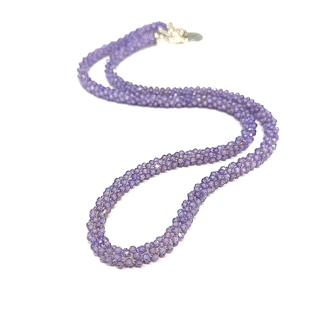 A purple zircon gemstone crocheted necklace with a sterling silver toggle, on a white background. A long front overview. 