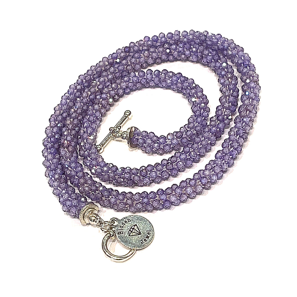A purple zircon gemstone crocheted necklace with a sterling silver toggle, on a white background. A spiral close-up overview. 
