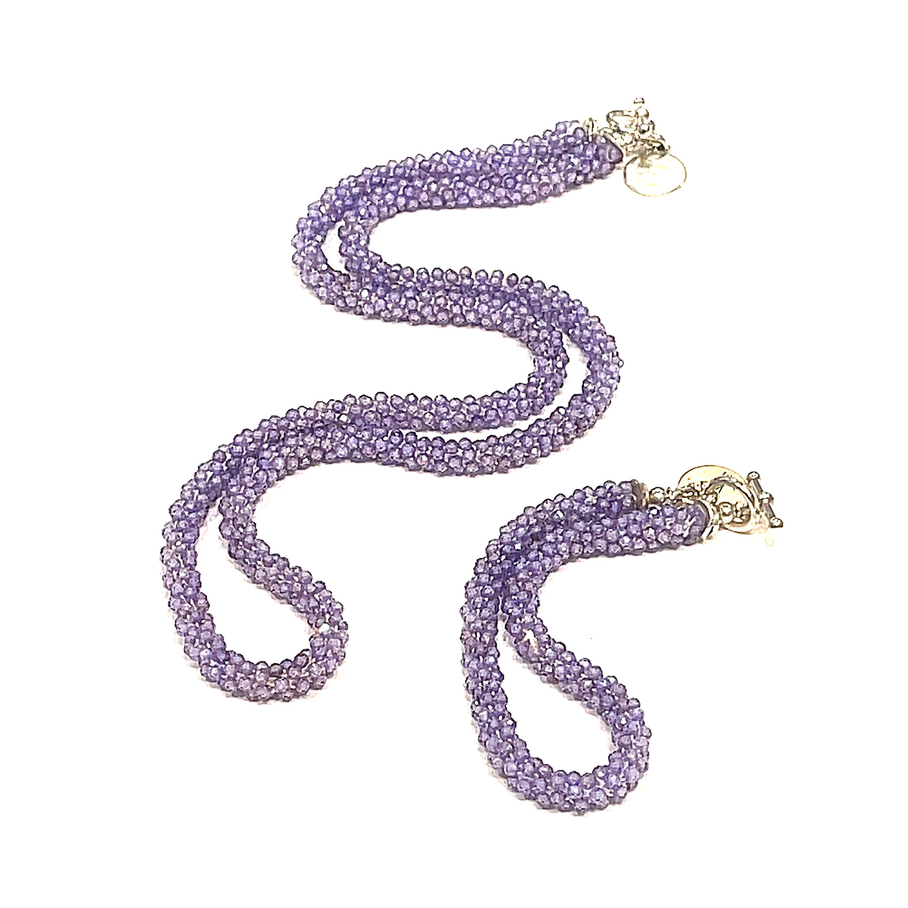 A purple zircon gemstone crocheted necklace with a sterling silver toggle, on a white background with its matching bracelet. A long front diagonal overview. 