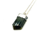 A raw Green Tourmaline pendant on a white background center hanging overview. 