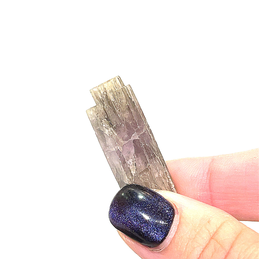A raw Spanish (Purple) Aragonite gemstones displayed in a models finger tips on a white background, front overview.