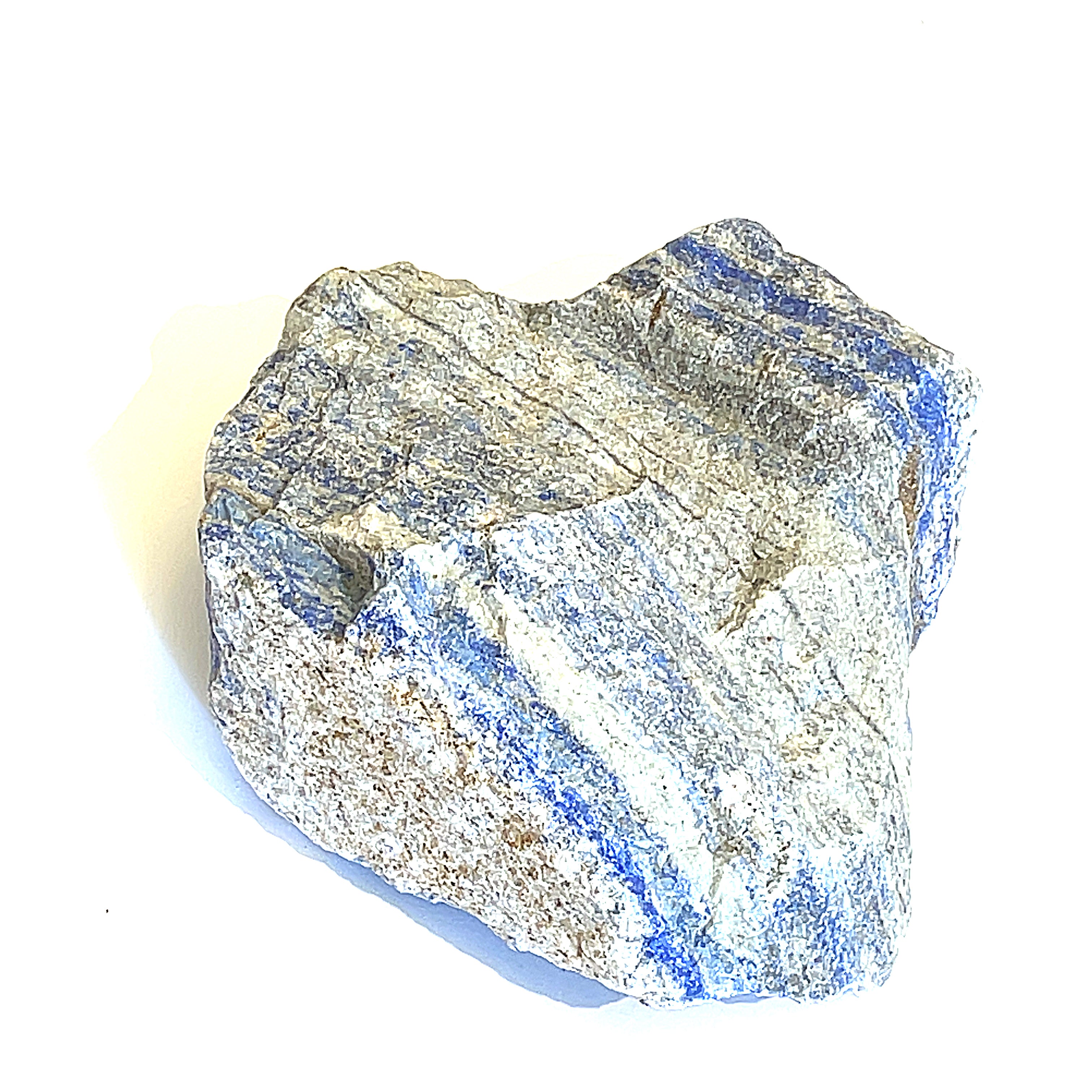 A rough, raw Lapis Lazuli gemstone with a distinctive blue color and gray matrix on a white background, front overview. 