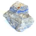 A rough, raw Lapis Lazuli gemstone with a distinctive blue color and gray matrix on a white background, front view. 