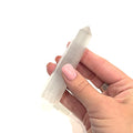 A selenite gemstone tower being held by a model on a white background, front overview. 