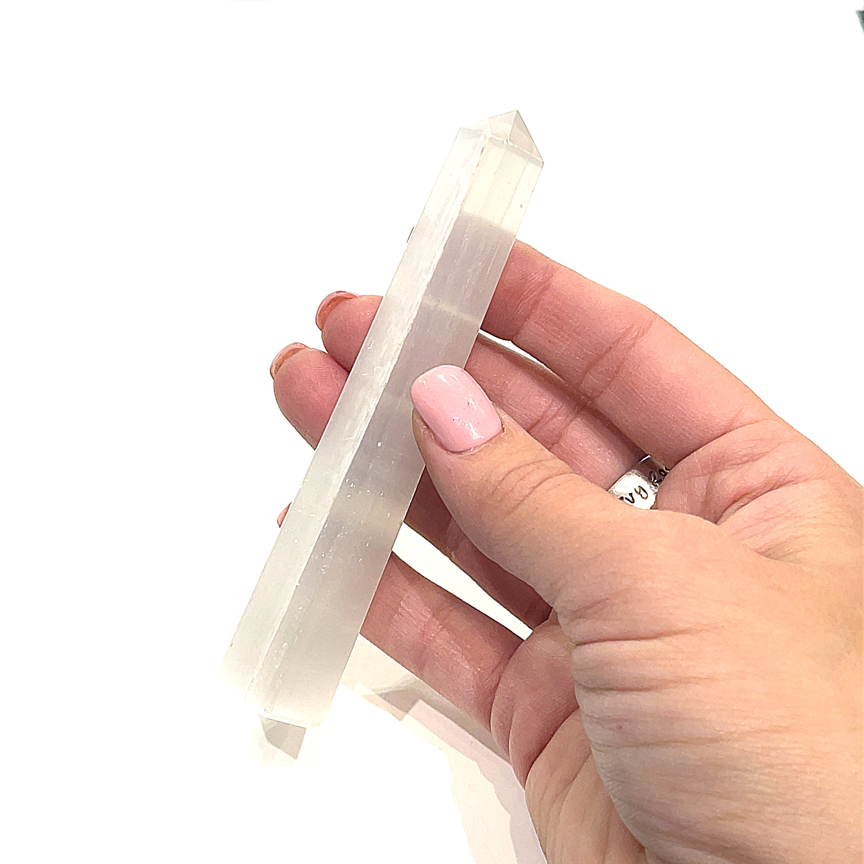 A selenite gemstone tower being held by a model on a white background, side overview. 