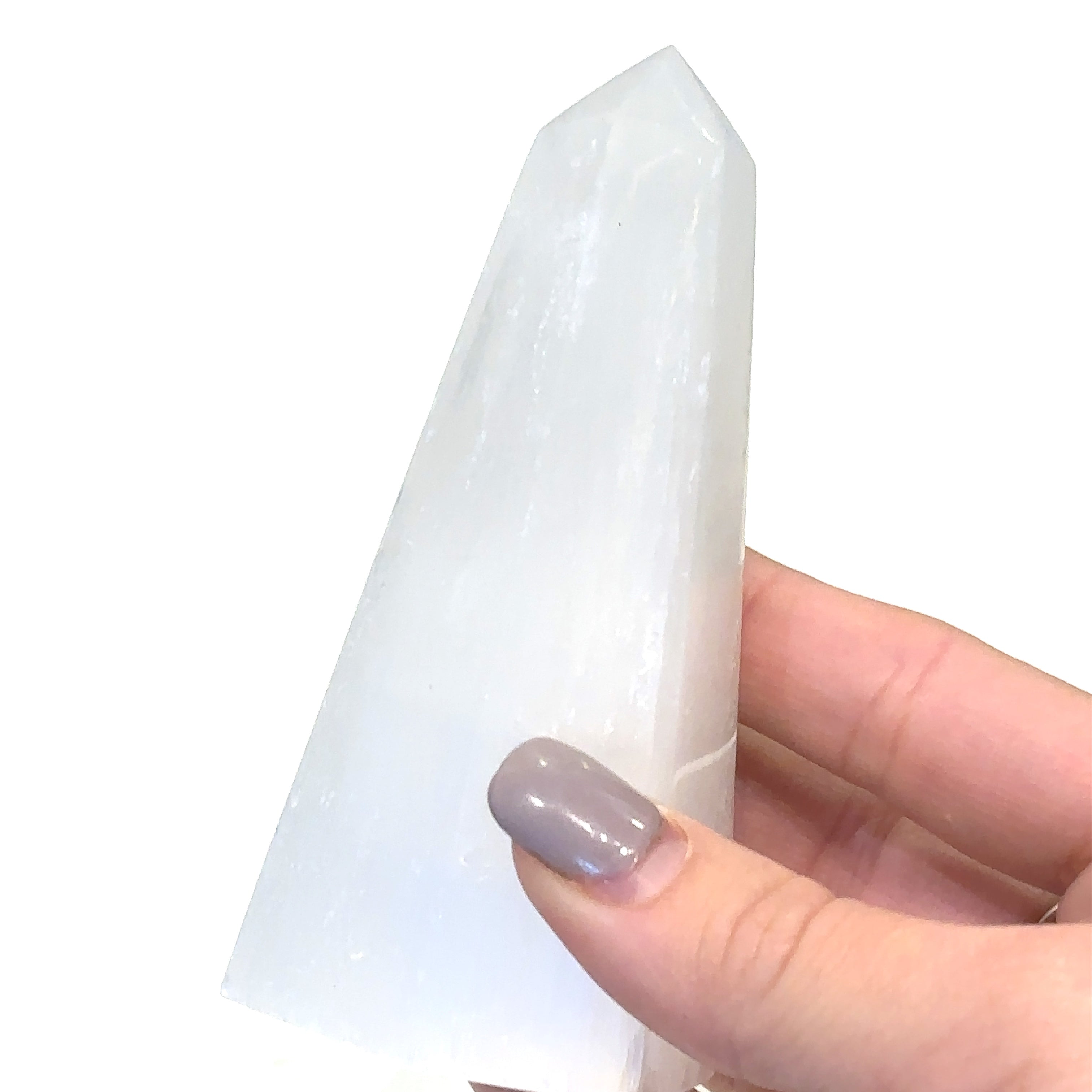A selenite gemstone towers displayed in a models hand on a white background, front close up overview. 