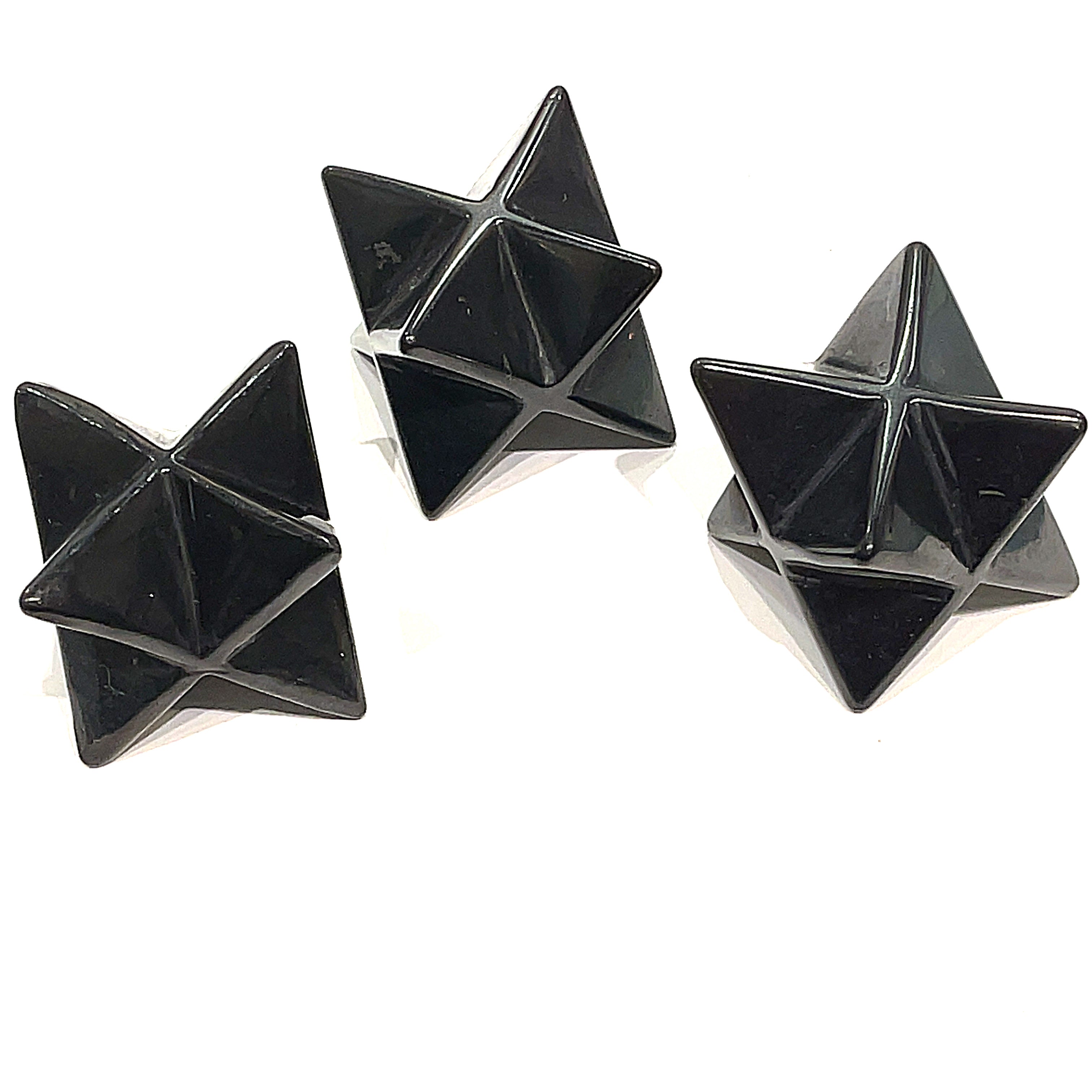 A set of three black Shungite gemstone merkaba carvings displayed against a white background, front overview. 