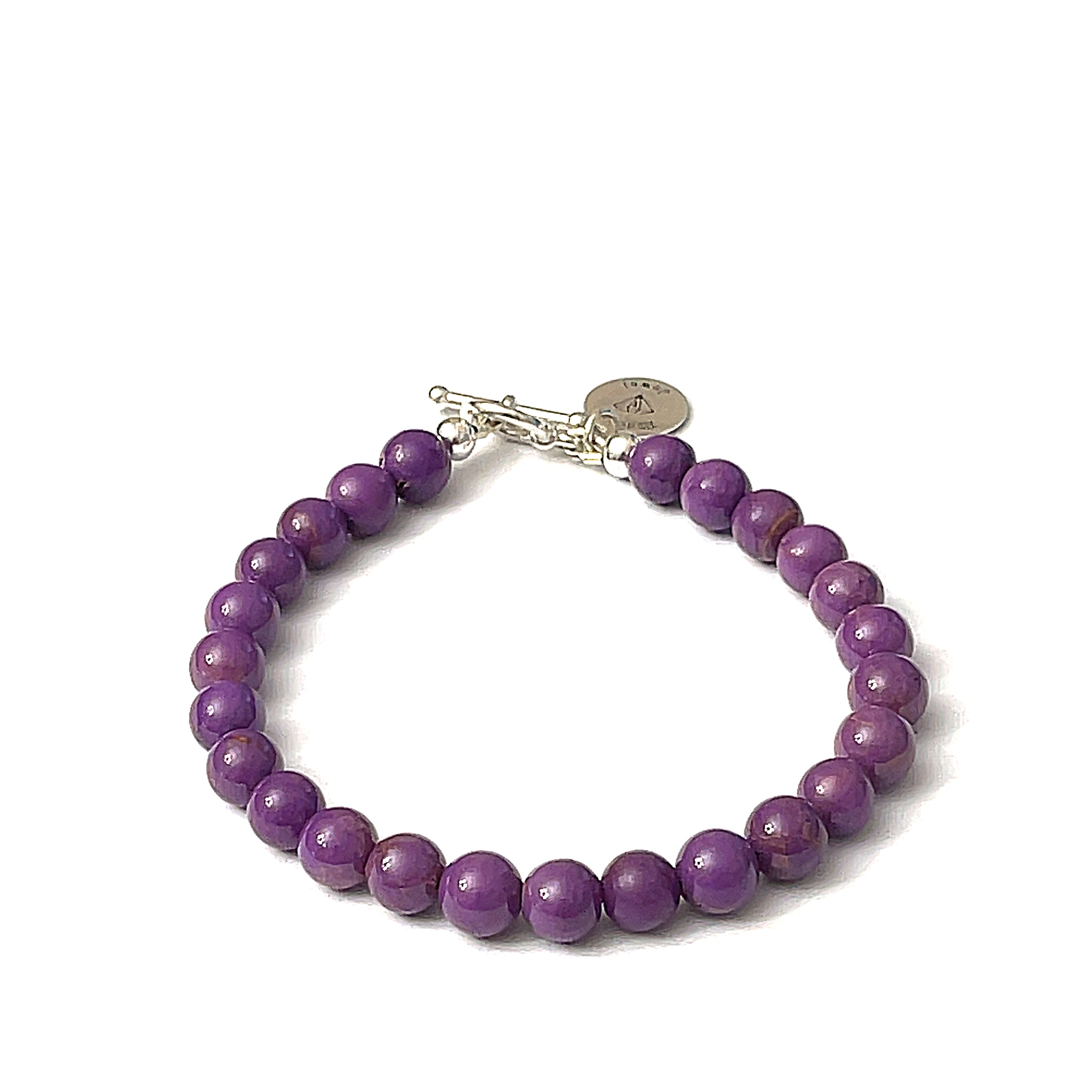 A sterling silver bracelet featuring a series of purple Phosphosiderite gemstones, with a toggle clasp, on a white background, overview. 
