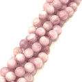 A strand of round pink Kunzite gemstone beads, on a white background, front long view. 