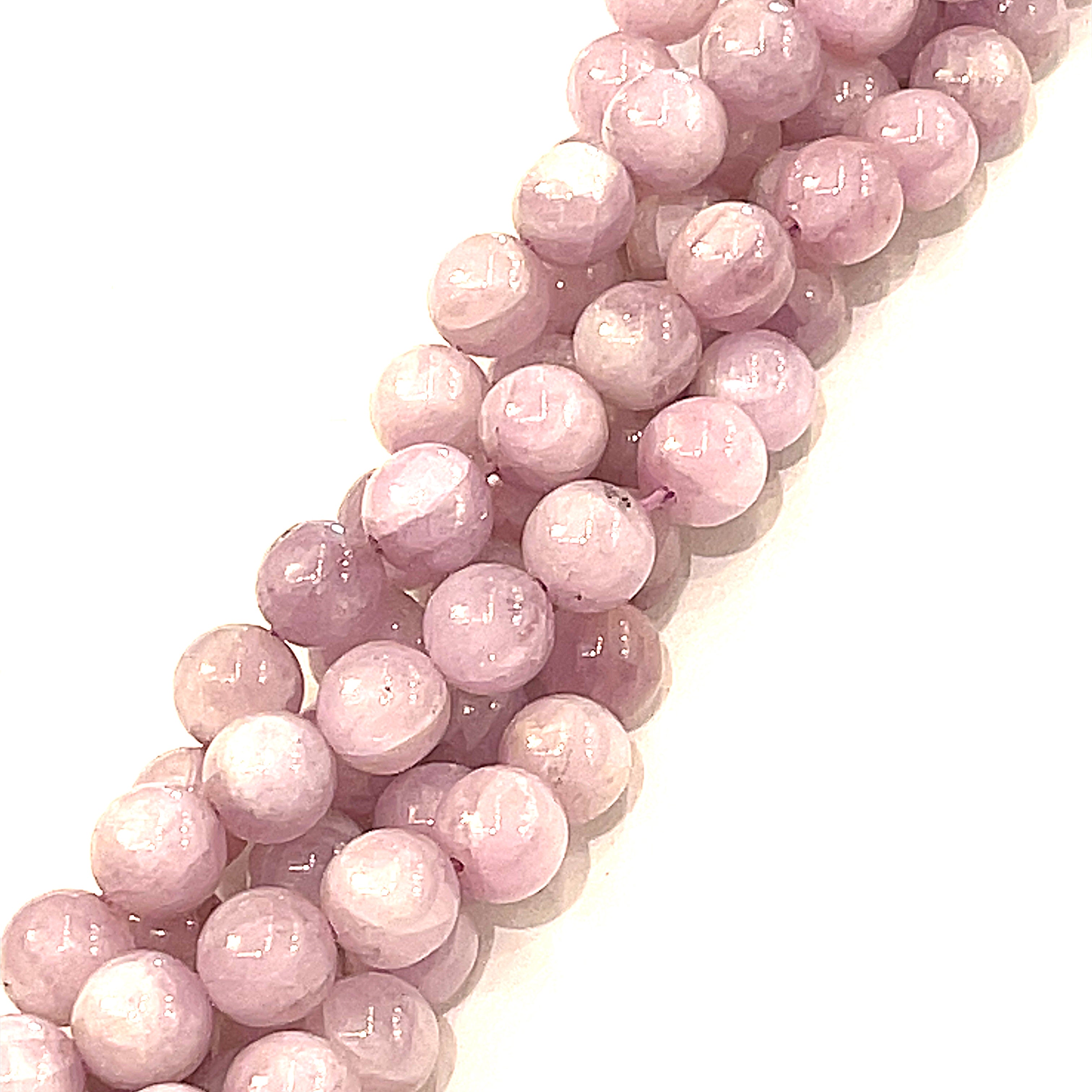 A strand of round pink Kunzite gemstone beads, on a white background, front long view. 