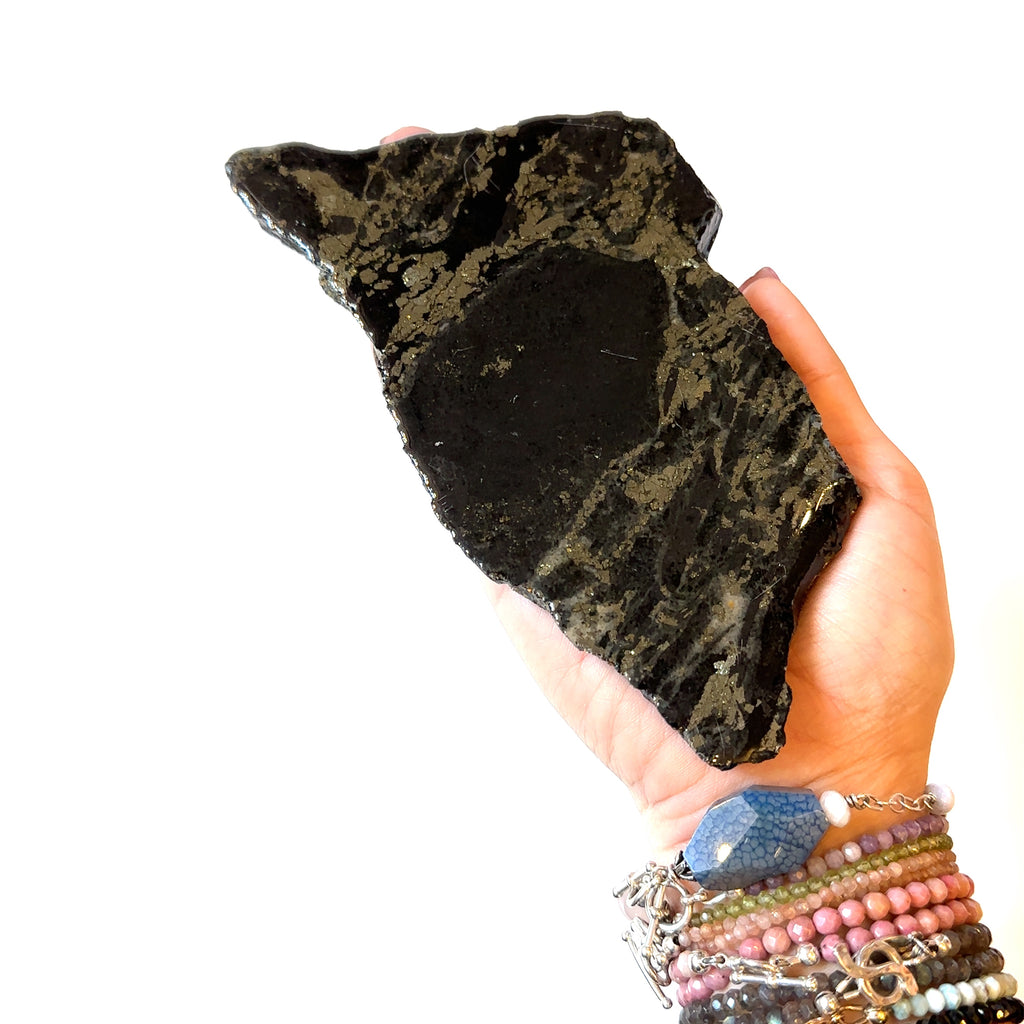 An Apache Gold gemstone in the model hand on a white background, in a close-up view of the front left angle.