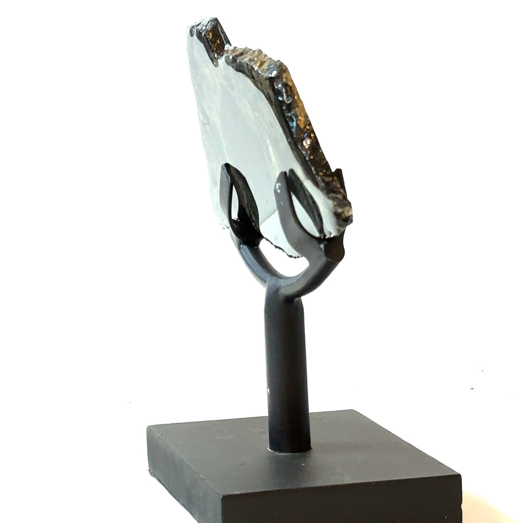 An Apache Gold gemstone on the metal stand on a white background, in a side view.