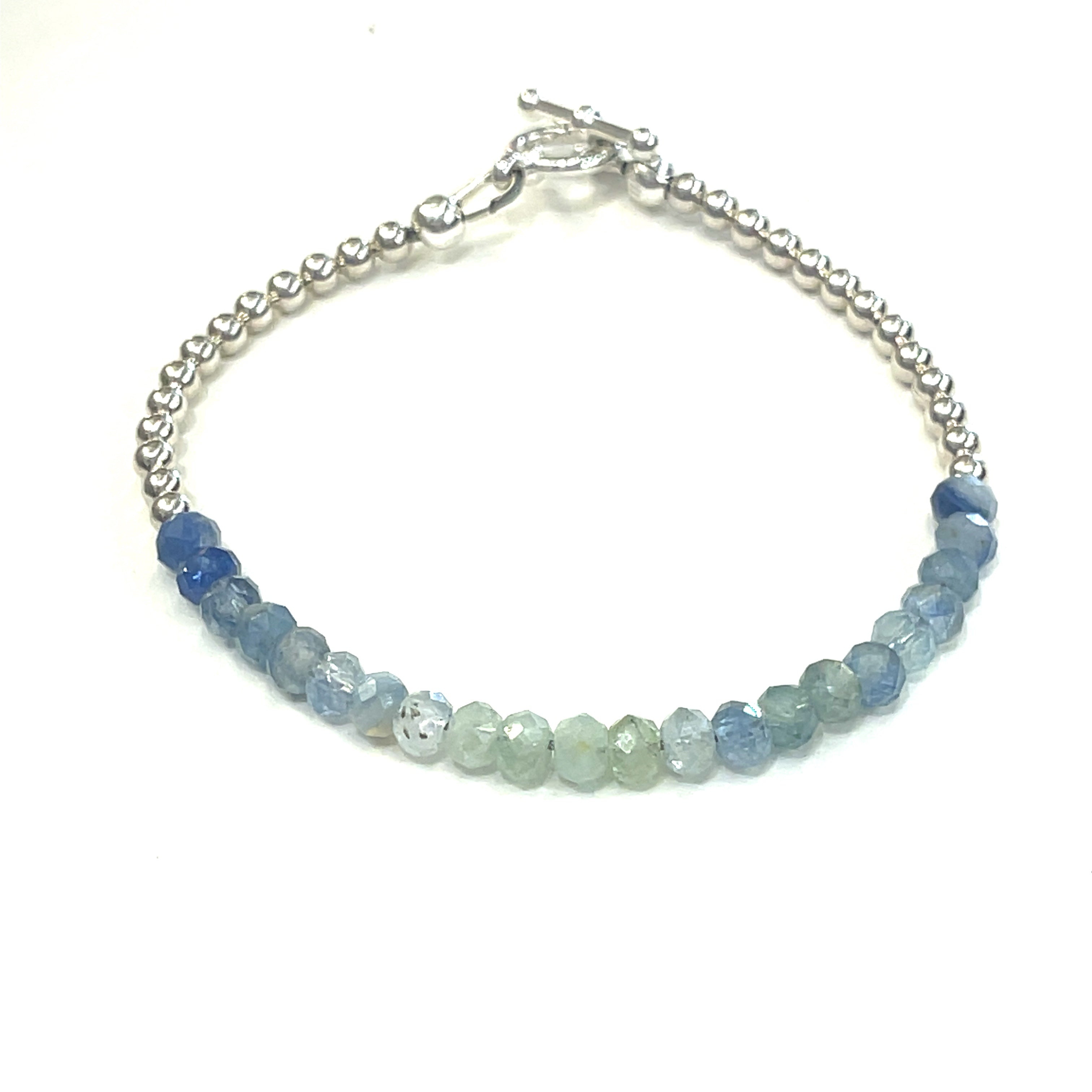 Blue and Green Kyanite faceted gemstone bracelet with sterling silver  beades on the end and toggle on a white background front, close up overview.