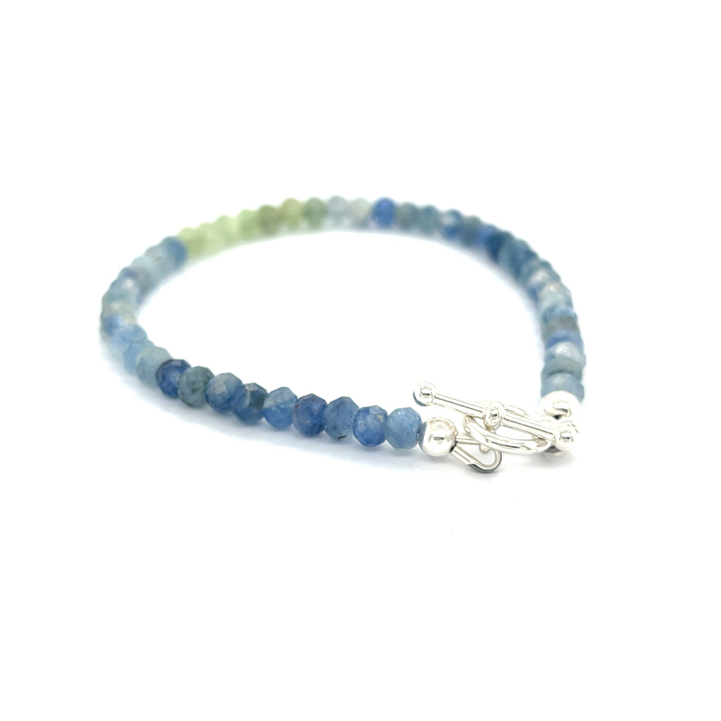 Blue and Green Kyanite faceted gemstone bracelet with sterling silver toggle on a white background back right angle overview. 