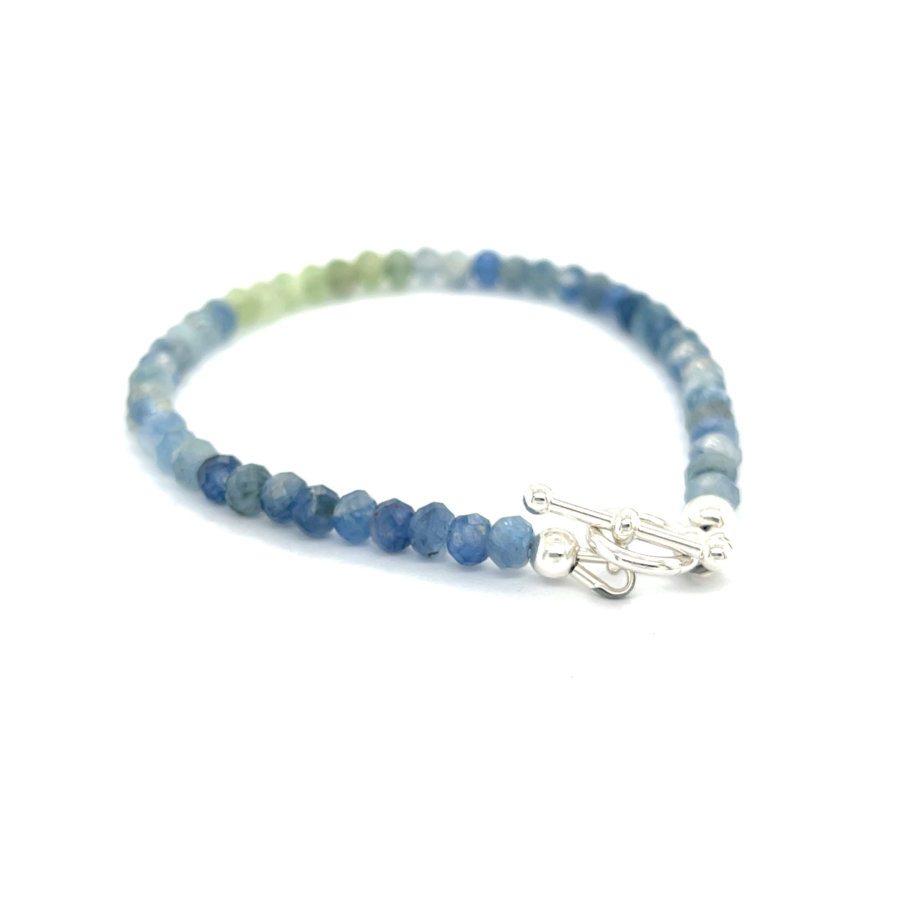 Blue and Green Kyanite faceted gemstone bracelet with sterling silver toggle on a white background back right angle overview. 
