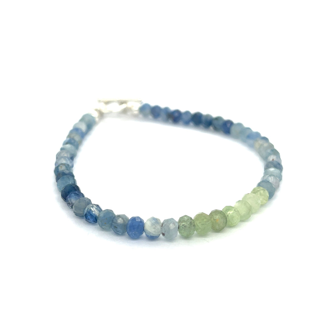 Blue and Green Kyanite faceted gemstone bracelet with sterling silver toggle on a white background front overview. 